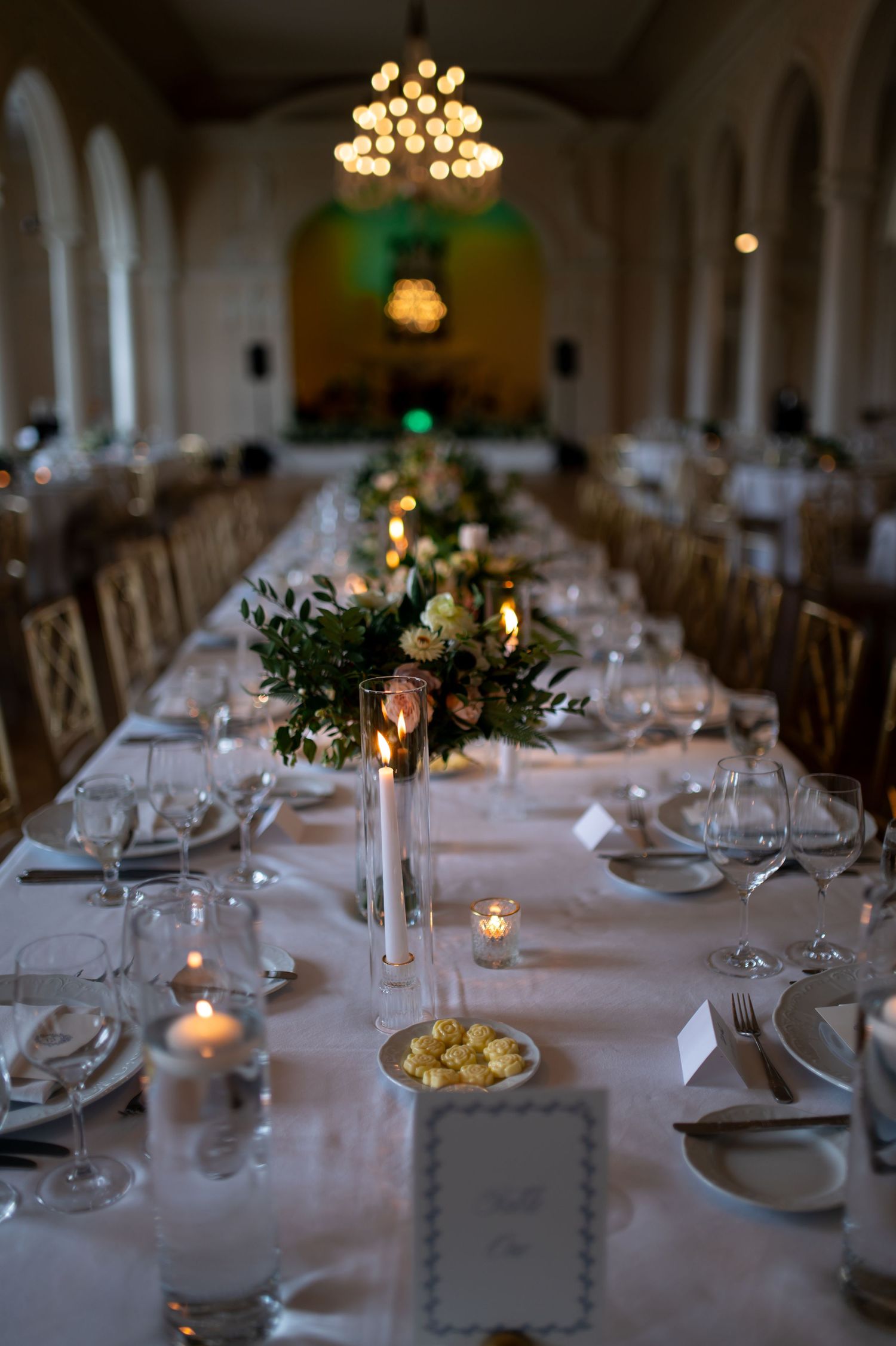 Romantic candlelit wedding reception tables with elegant place settings and floral centerpieces.