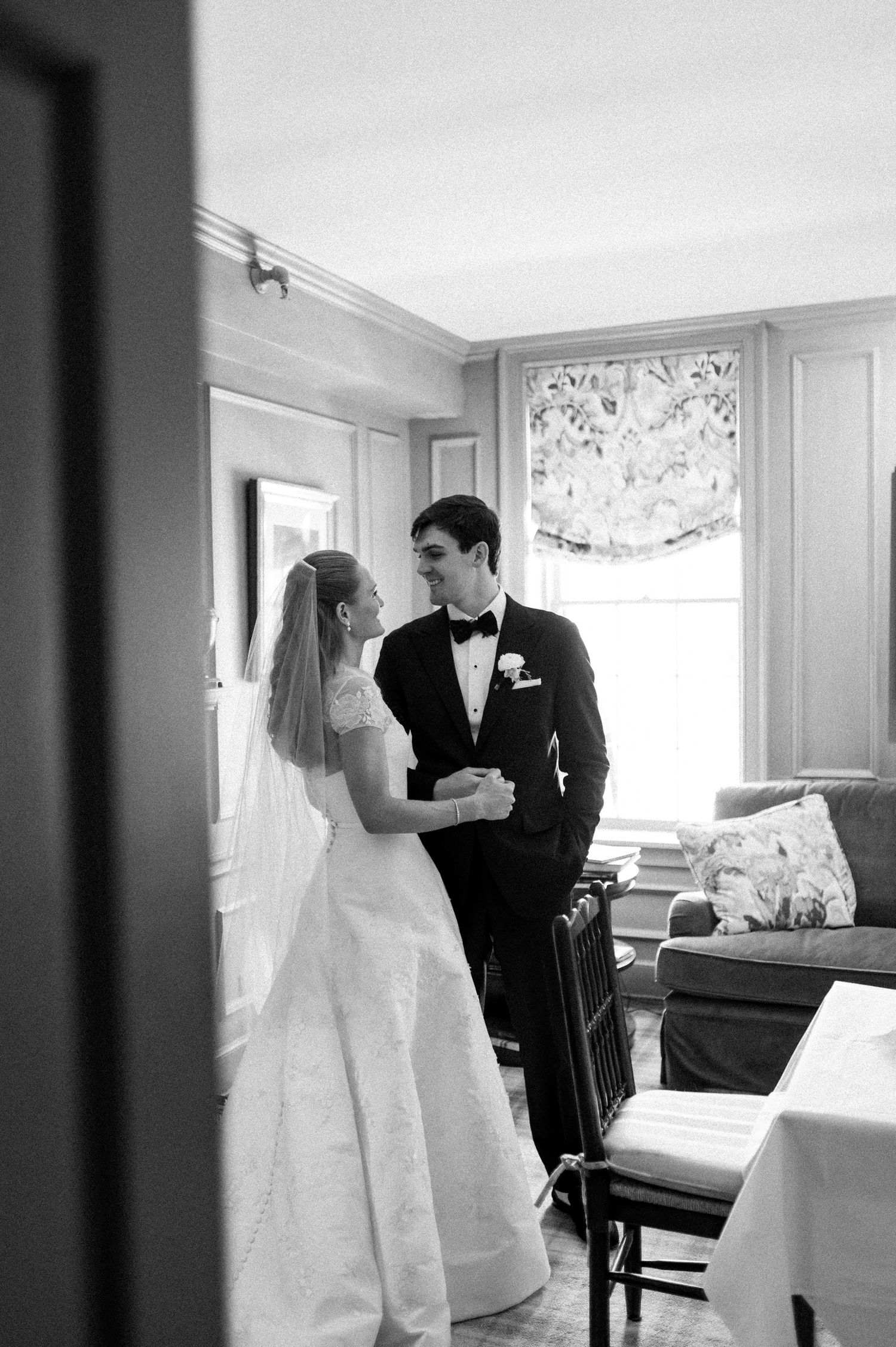 Bride and groom share a tender moment in black and white wedding portrait indoors.