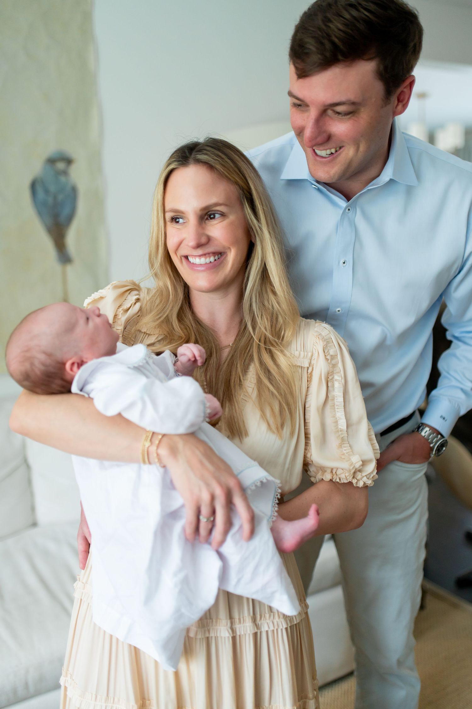 A couple shares a joyful moment with their newborn baby in a bright interior setting.