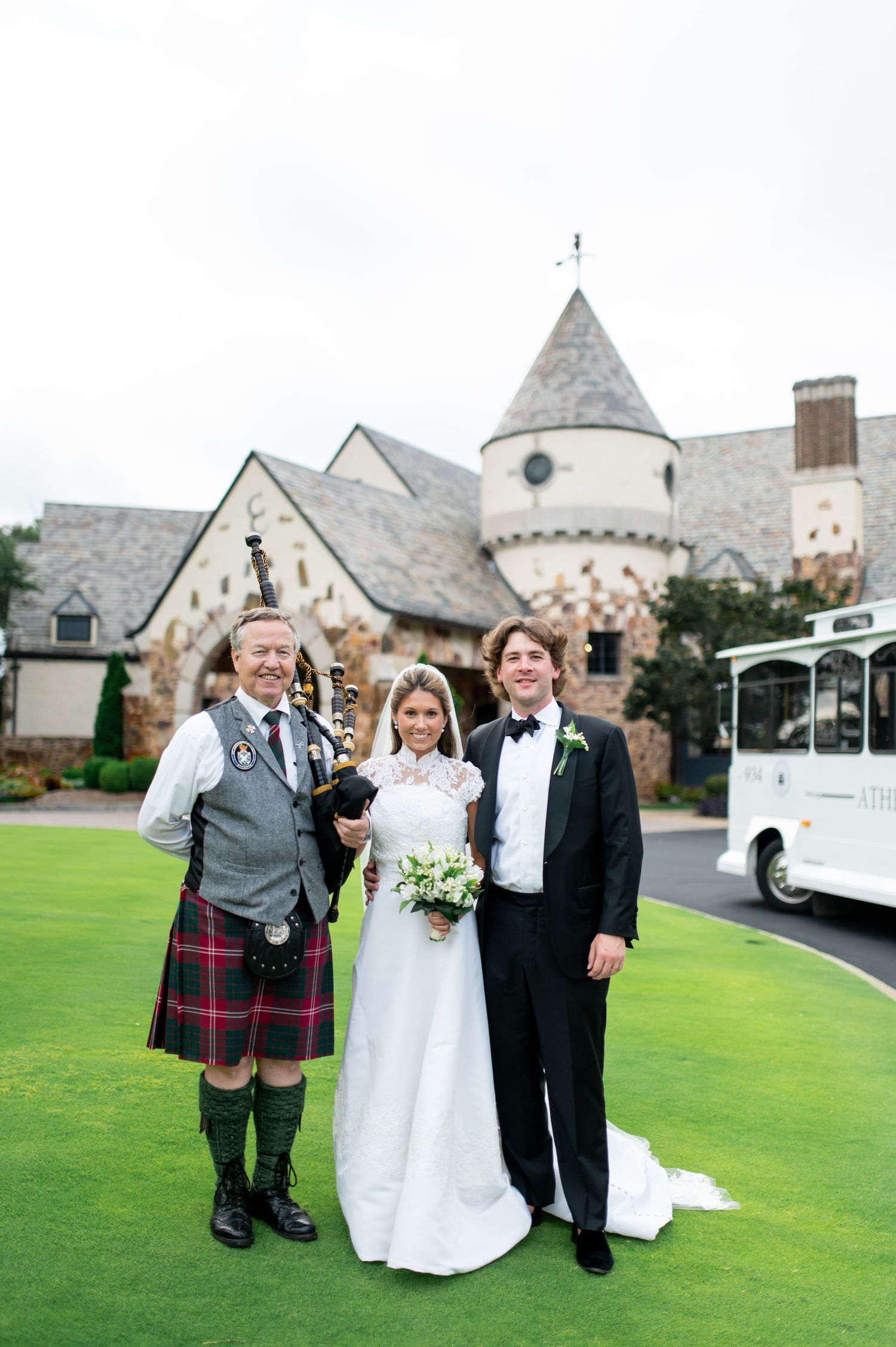 Wedding photo with man in traditional Scottish kilt outside stone church with turret.