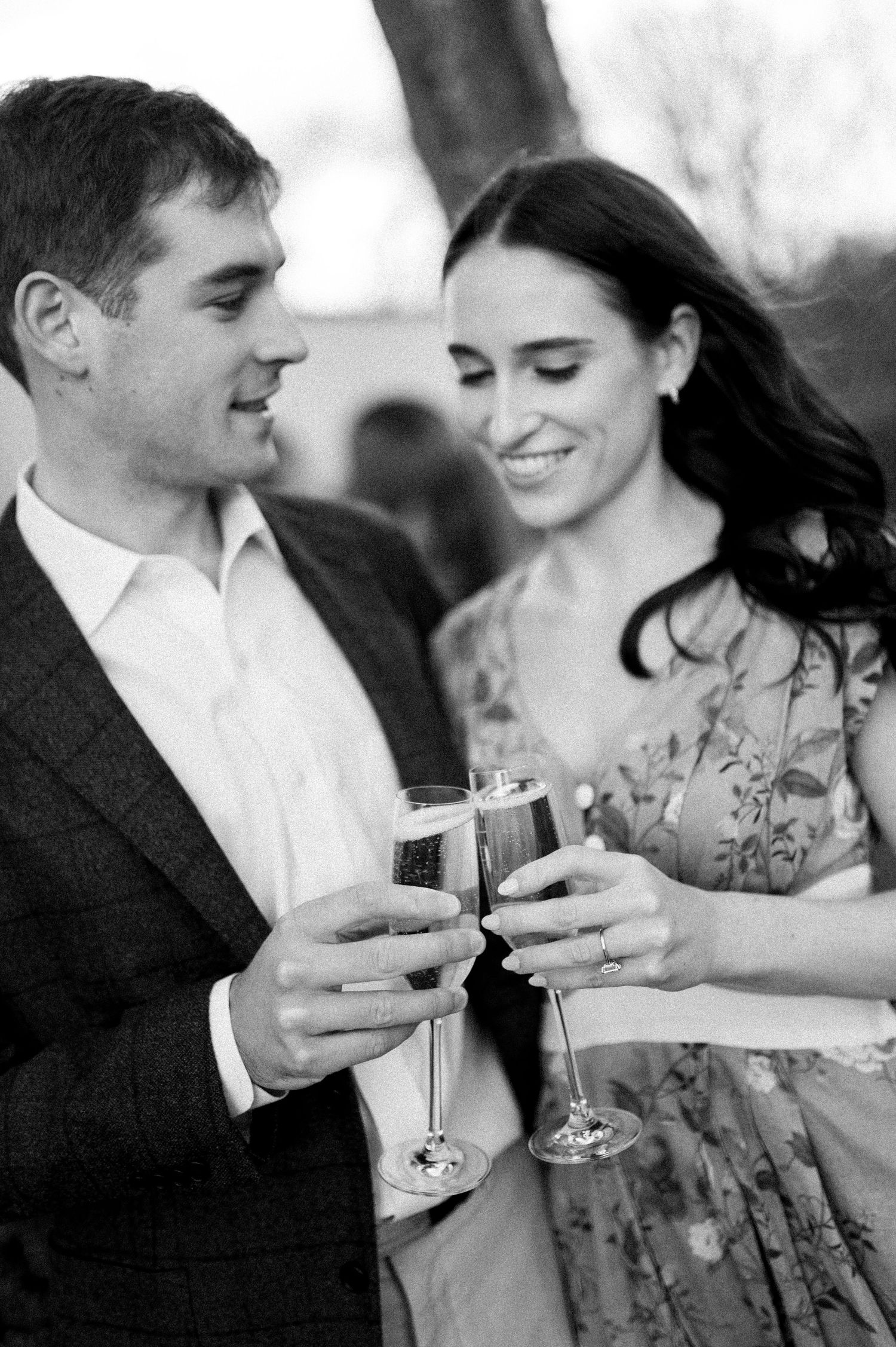 A couple toasts with wine glasses during an elegant outdoor engagement session.