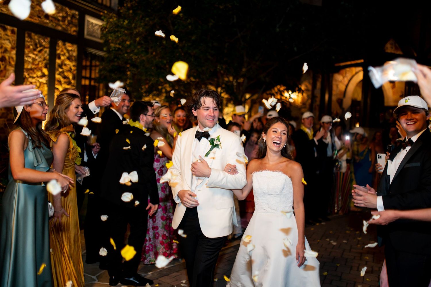 Wedding reception celebration with guests dancing and mingling under warm lighting.