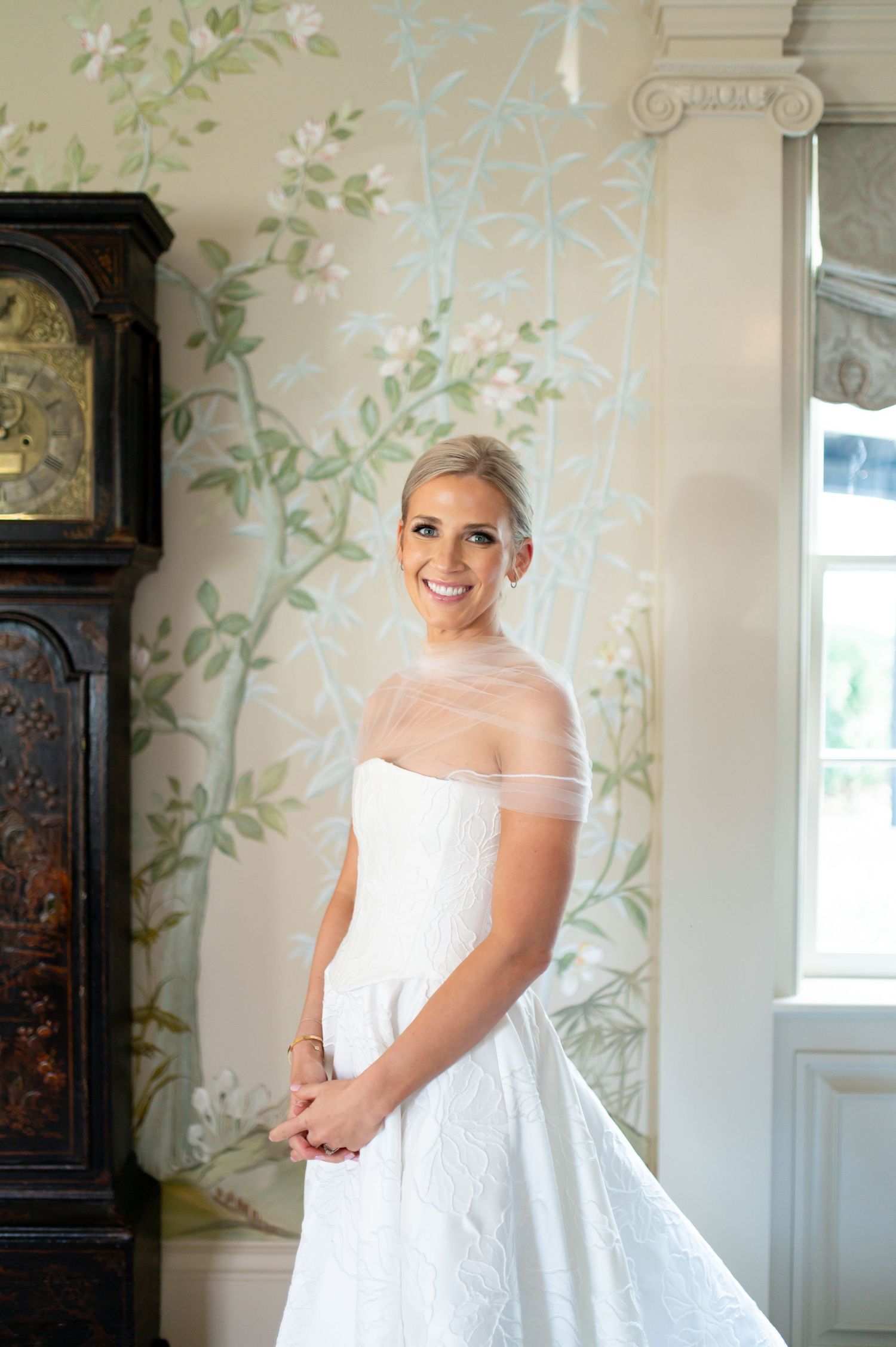 Elegant bridal portraits in a room with delicate floral wallpaper and natural lighting.