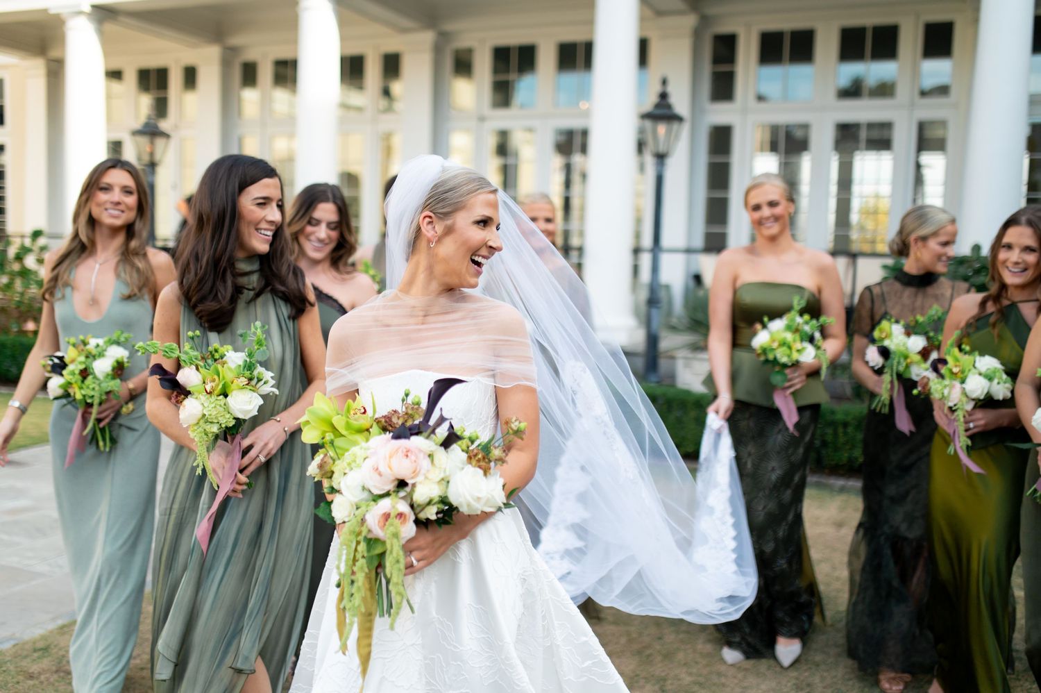 Wedding party poses and celebrates together on elegant columned veranda.