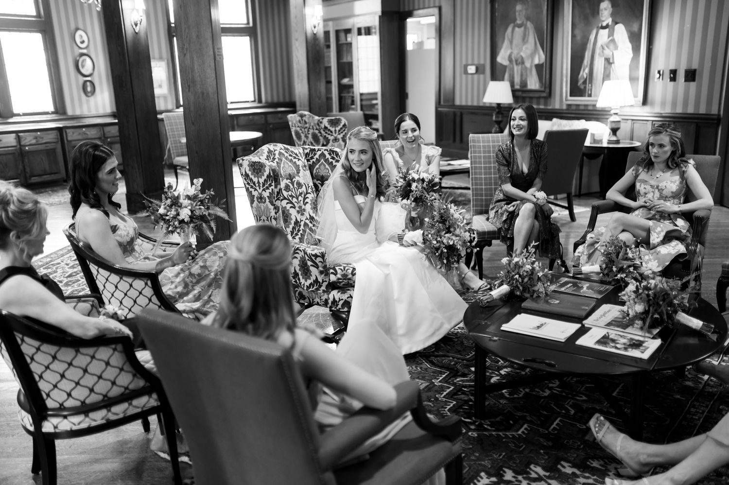 Black and white photo of wedding party preparations in a cozy interior setting.