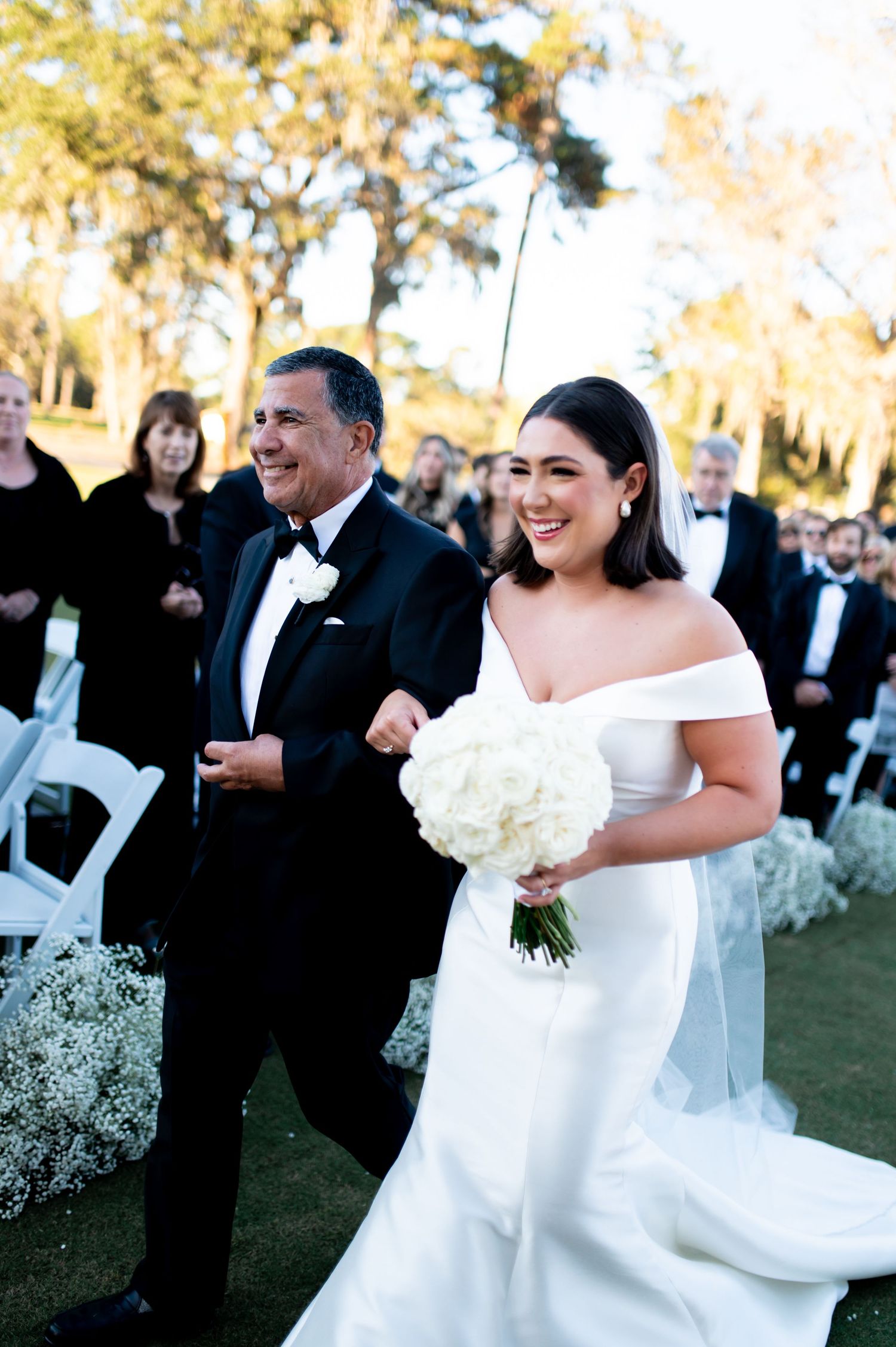 A joyful wedding celebration on a sunny day with guests in formal attire.