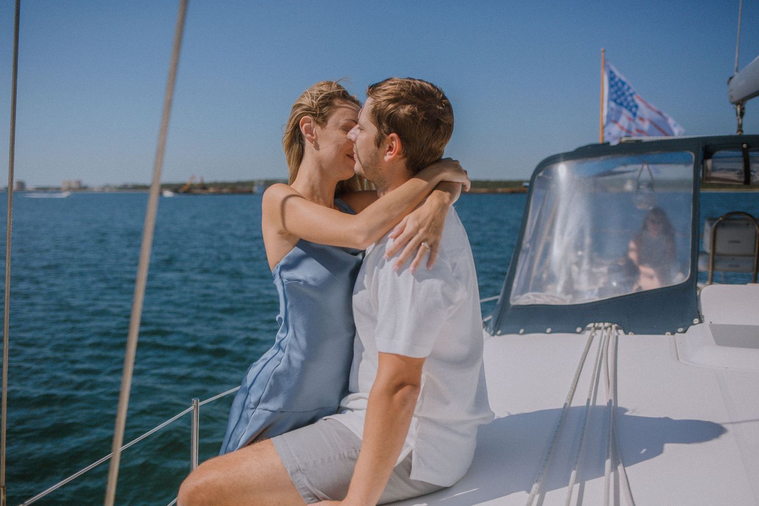 Romantic couple kissing on a white sailboat on a sunny day.