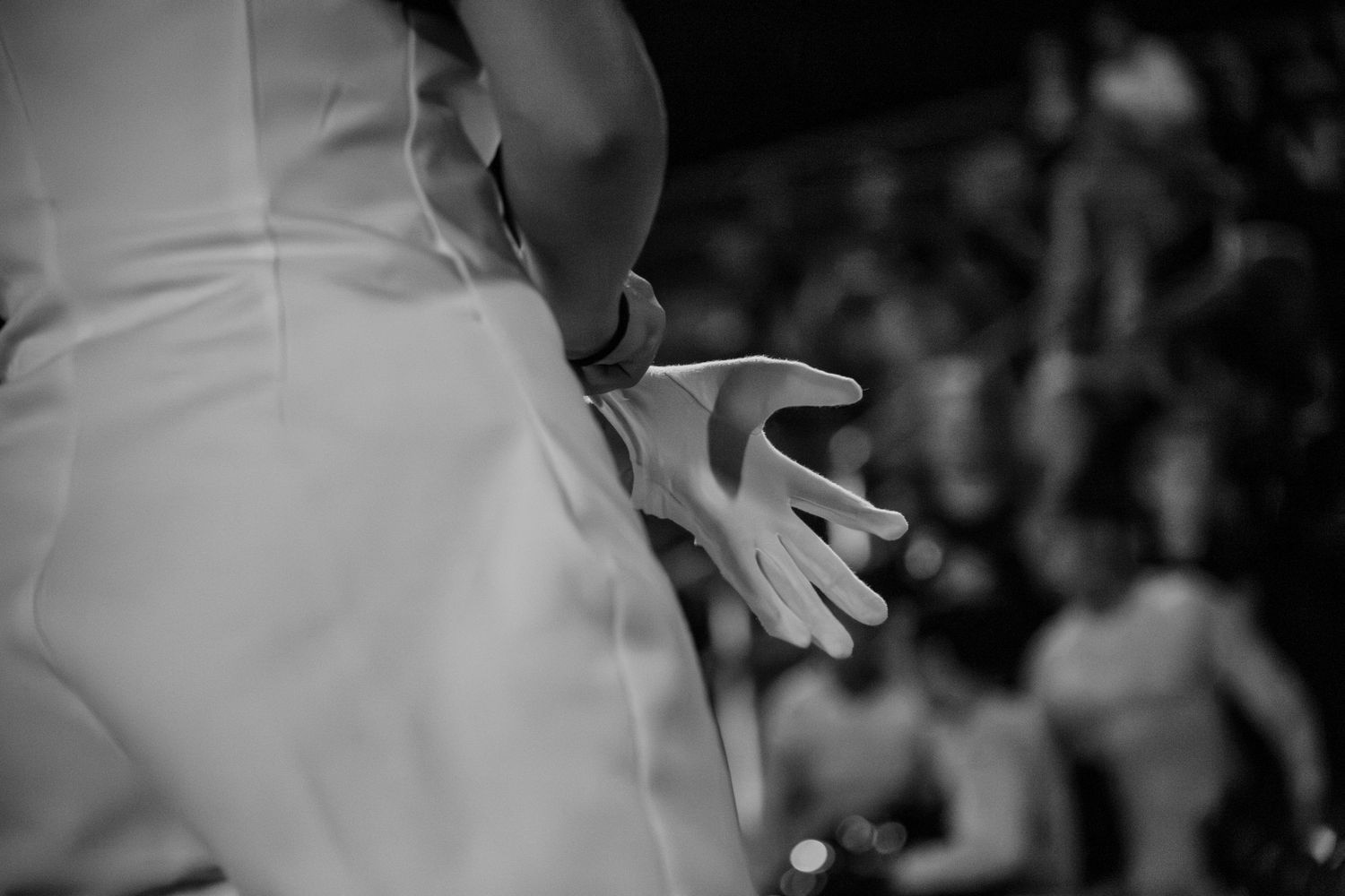Black and white photo of a bride's hand and wedding dress detail at a wedding ceremony.