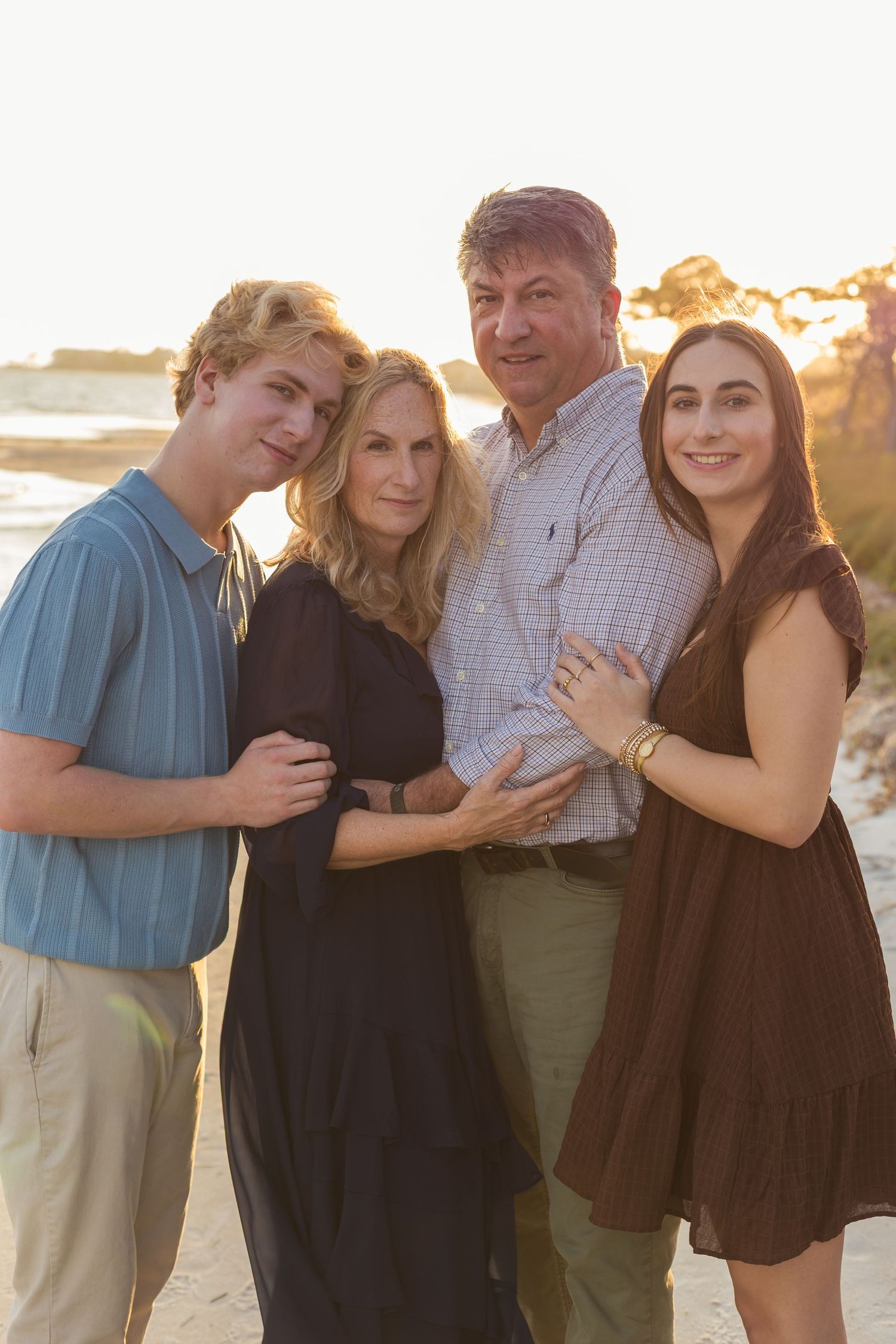 family cuddled together on the beach at sunset
