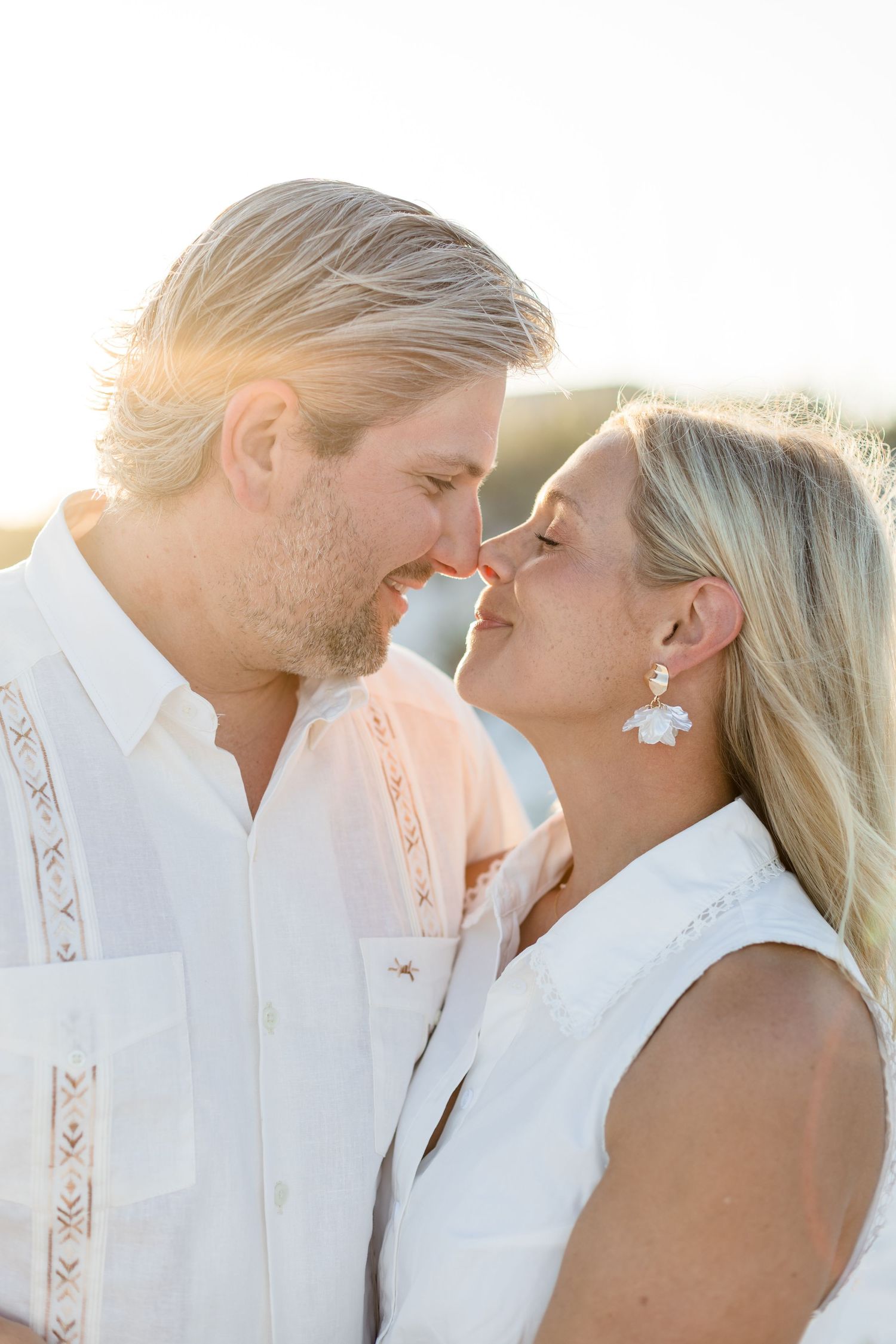 Romantic blond couple sharing a close moment in warm golden sunset light.