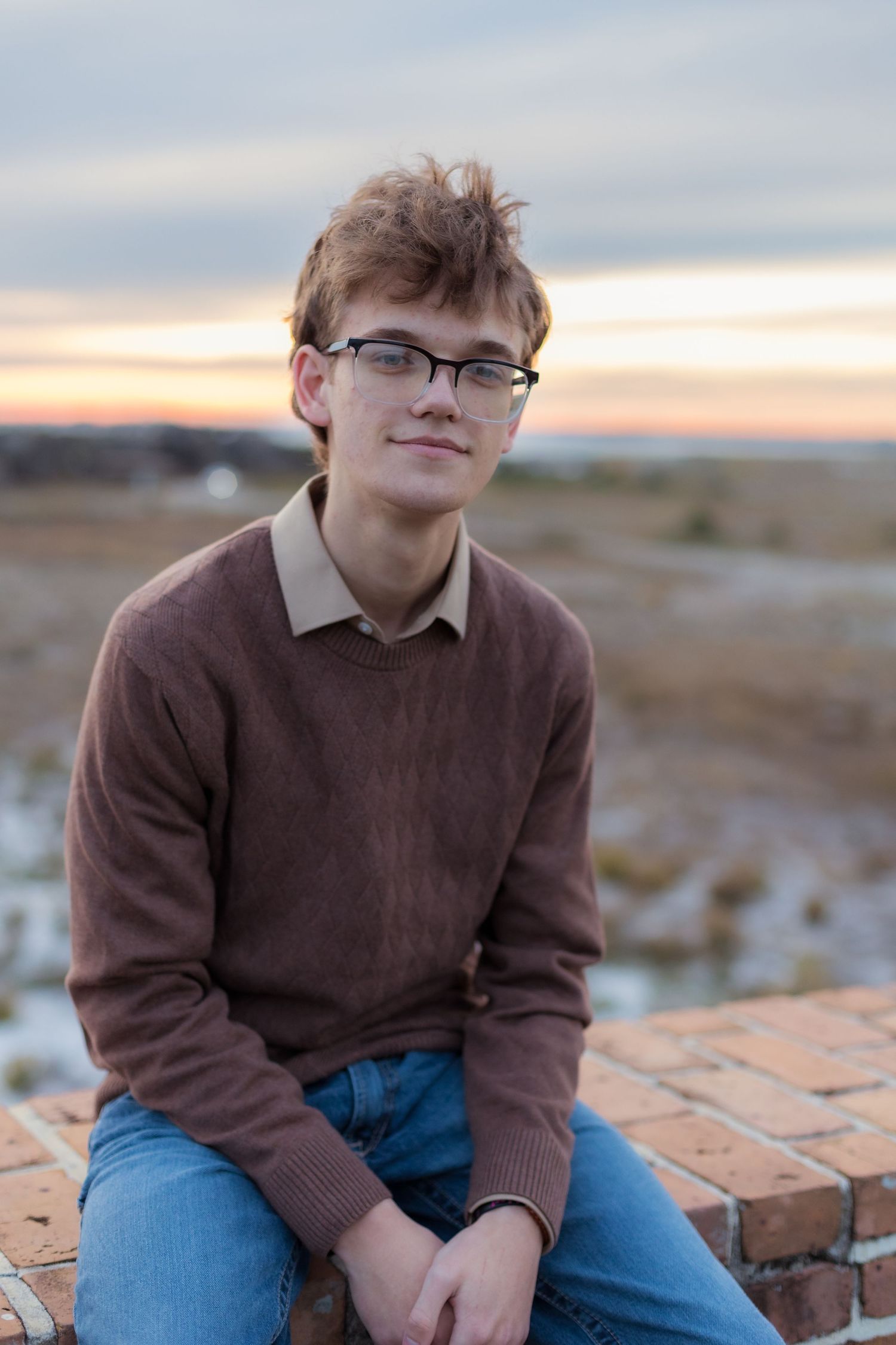 young man sitting on a brick wall at the beach