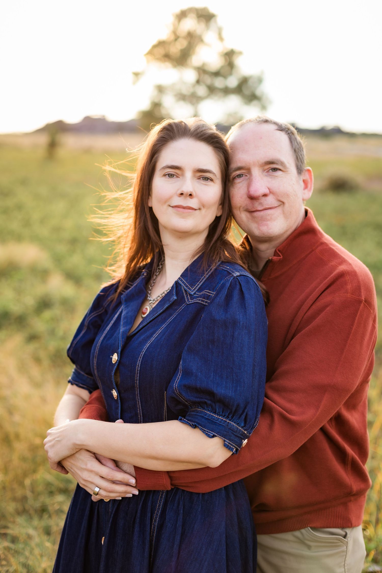 couple hugging in a field with sunshine