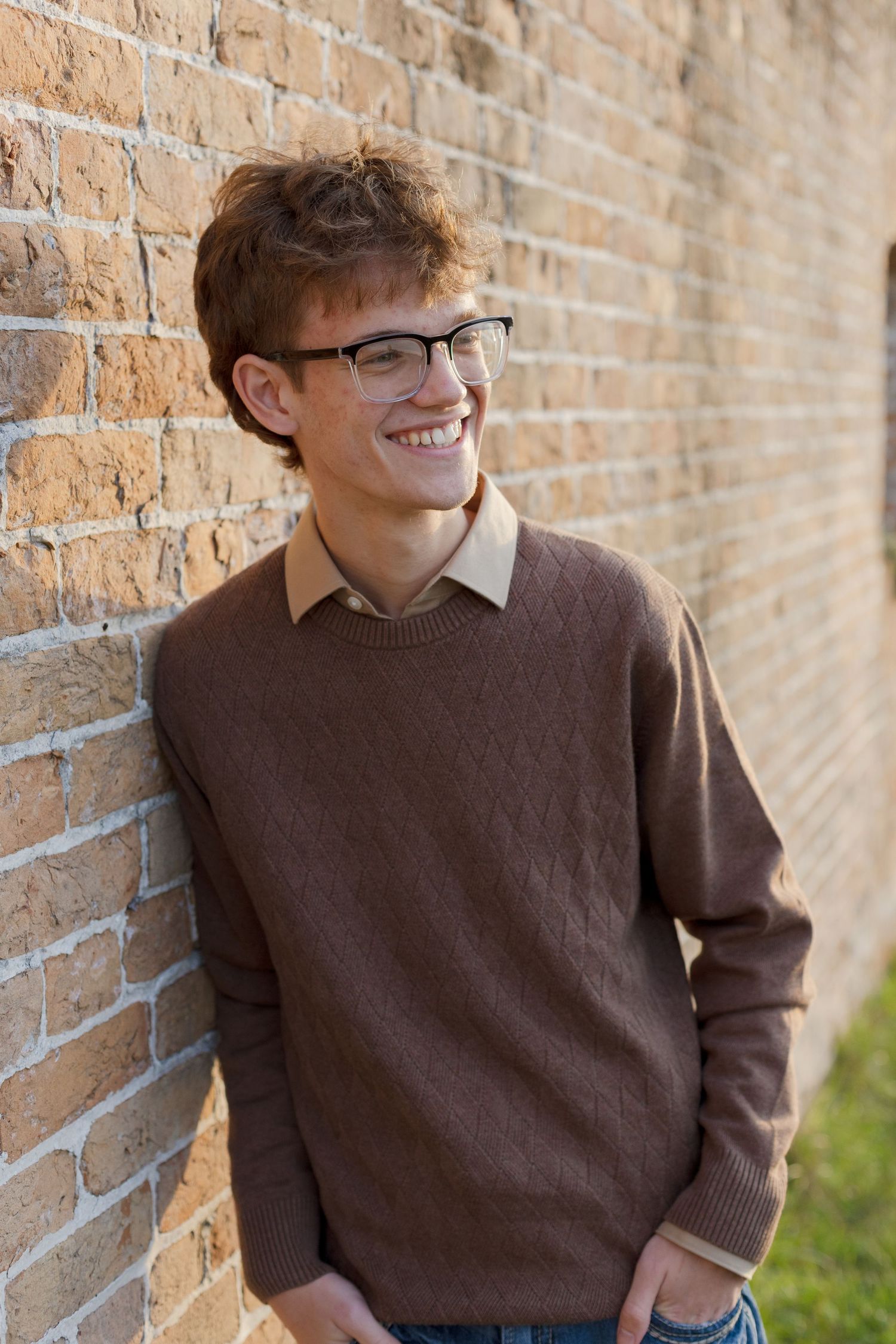 young man laughing against brick wall