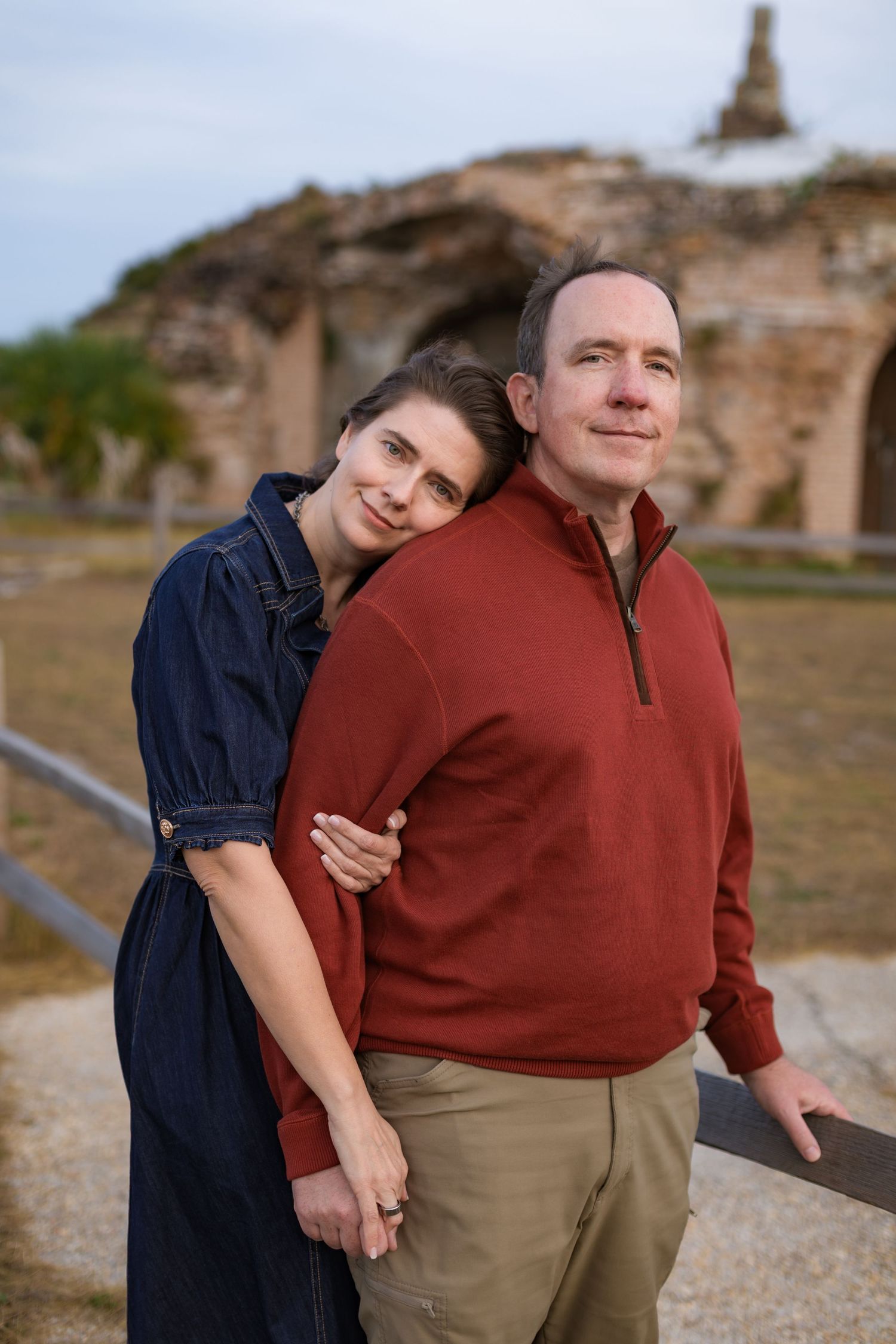 couple holding each other in front of brick arches