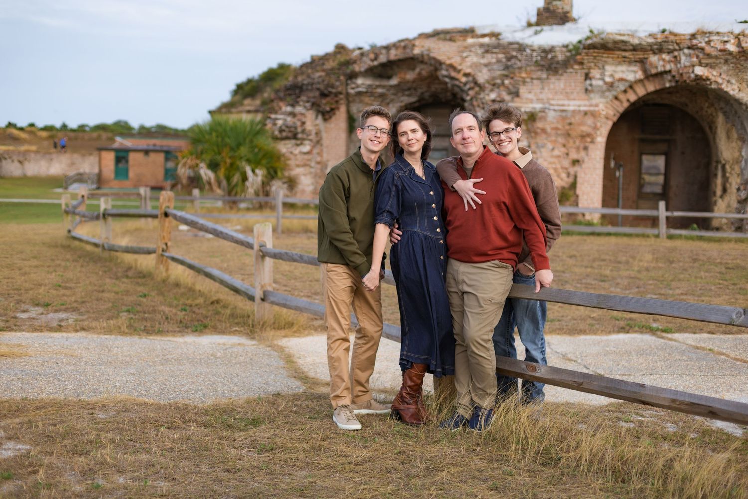 family holding each other in front of wooden fence and bricks