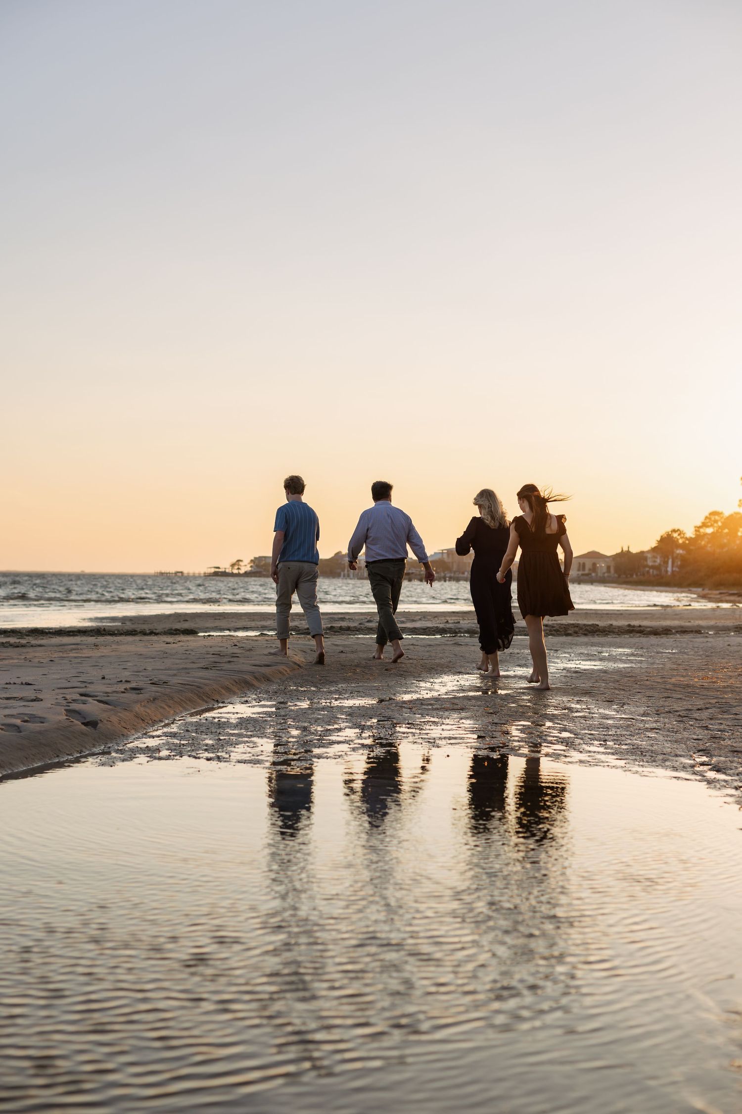 family walking in shallow water at the beach at sunset