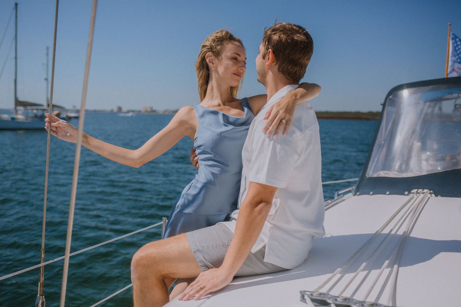 Couple embracing on a sailboat on a sunny day on the ocean.
