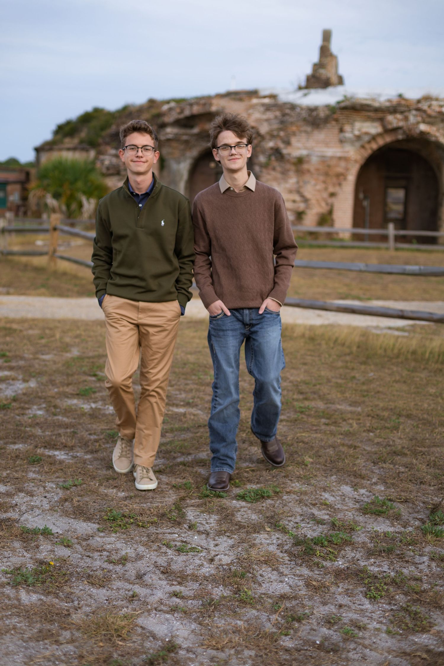 young men walking in front of brick wall