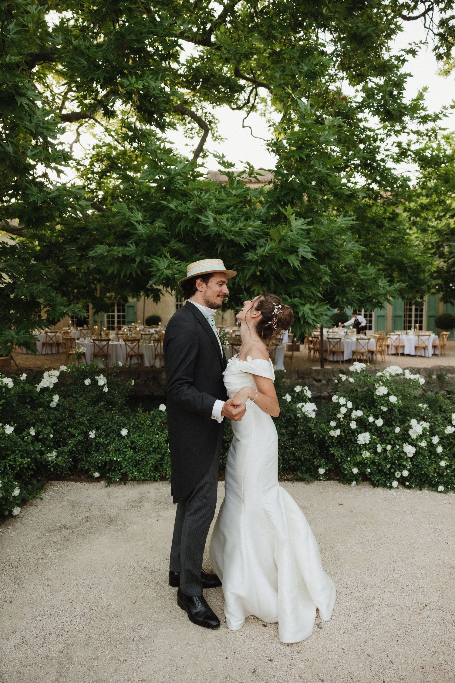 A romantic outdoor wedding moment captured in a garden setting with white flowers and lush greenery.
