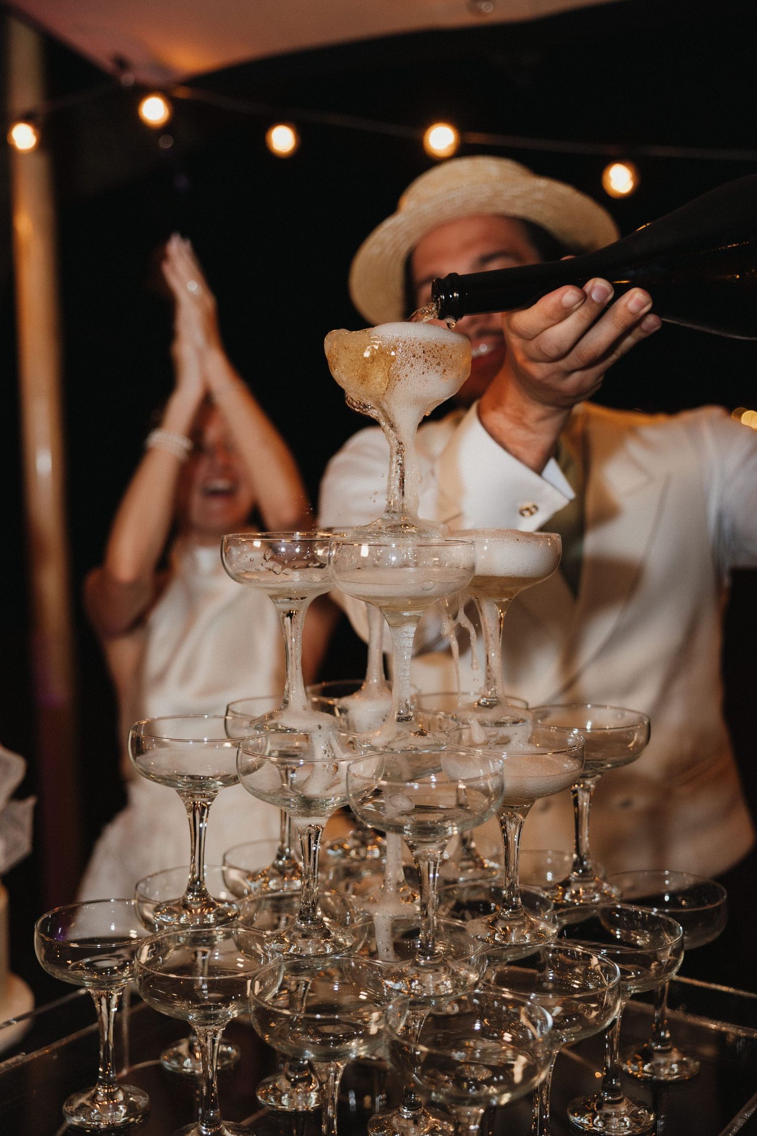 Champagne being poured into a tower of vintage coupe glasses at an elegant event.