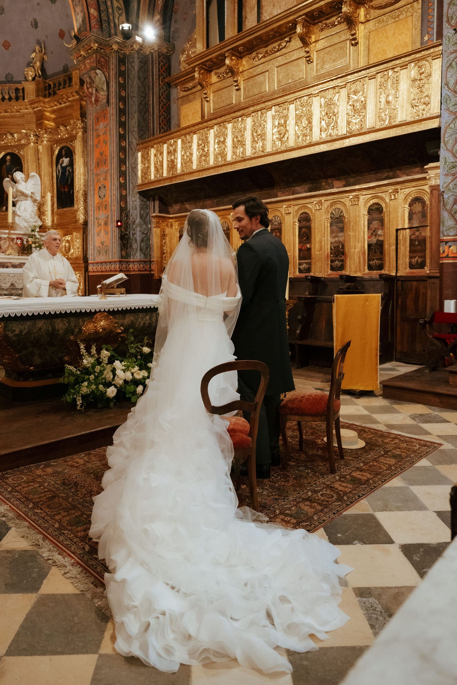 Elegant church interior with checkered floor and gilded details during a wedding ceremony.