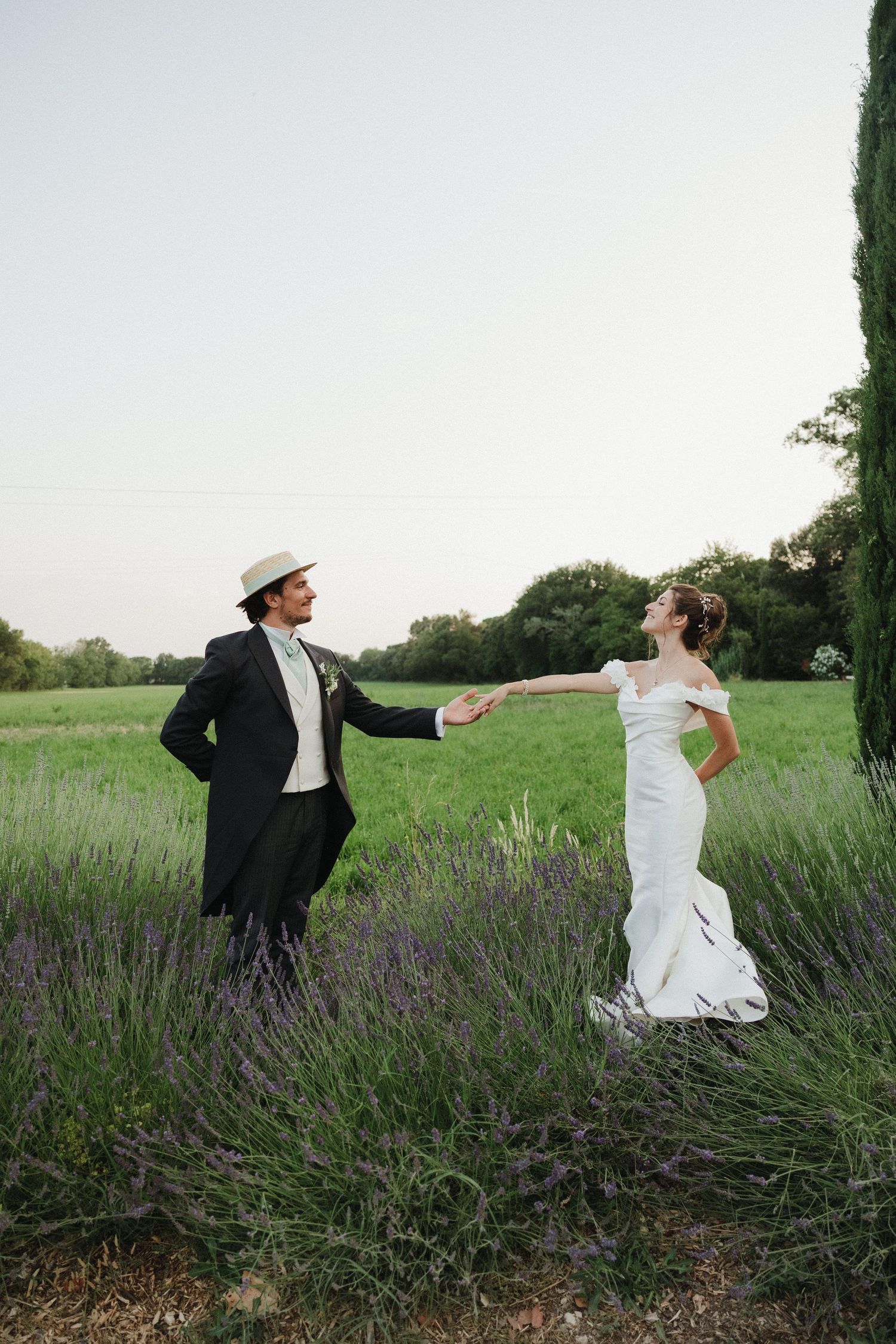 A playful wedding photo in a lavender field with the couple striking dynamic poses.