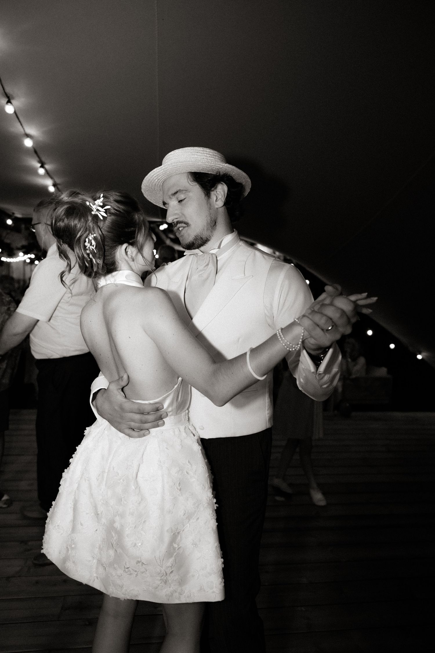 Black and white photos show couple dancing intimately at nighttime wedding reception.