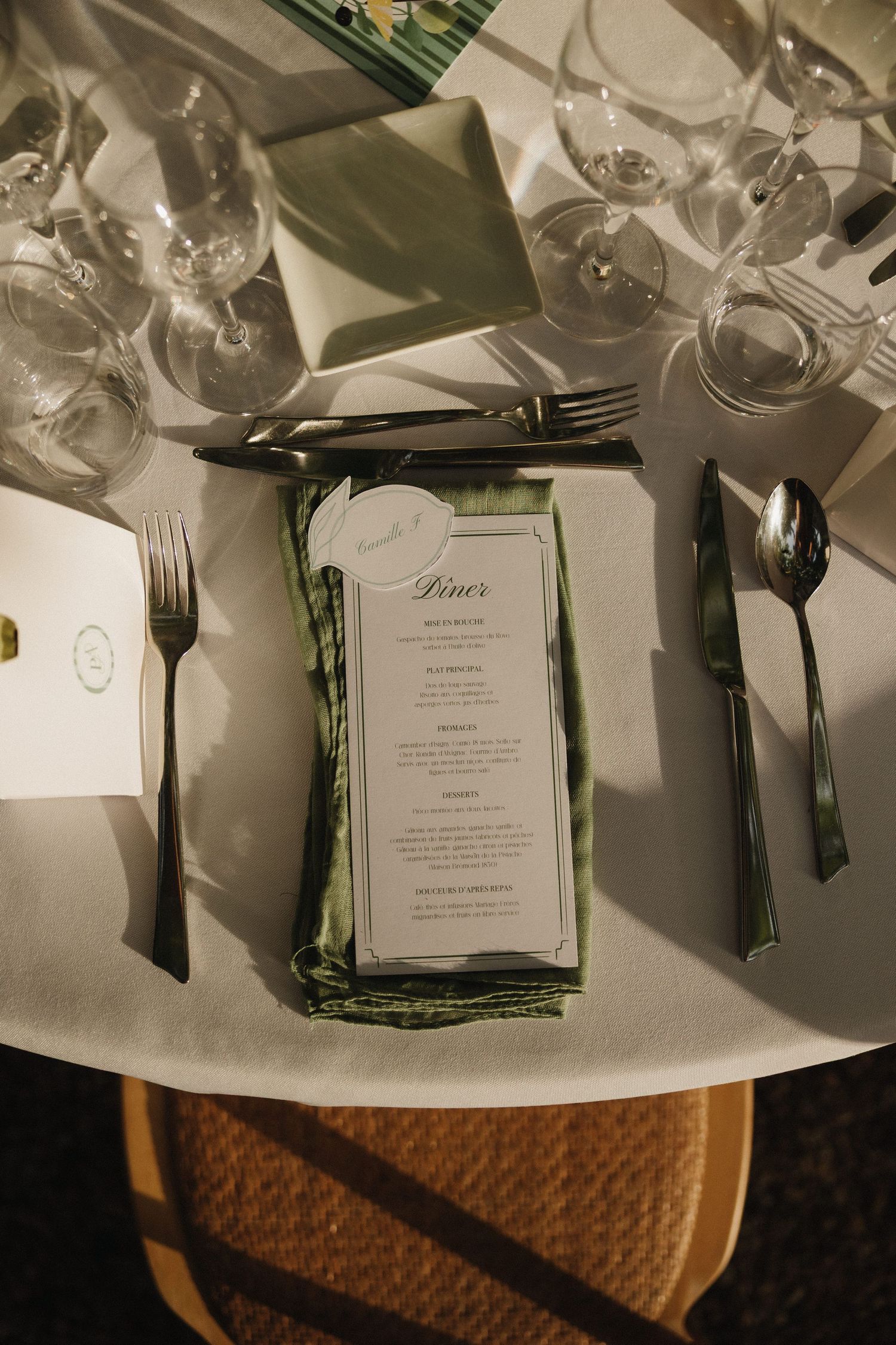 Formal table setting with wine glasses and printed menus arranged on white tablecloth.
