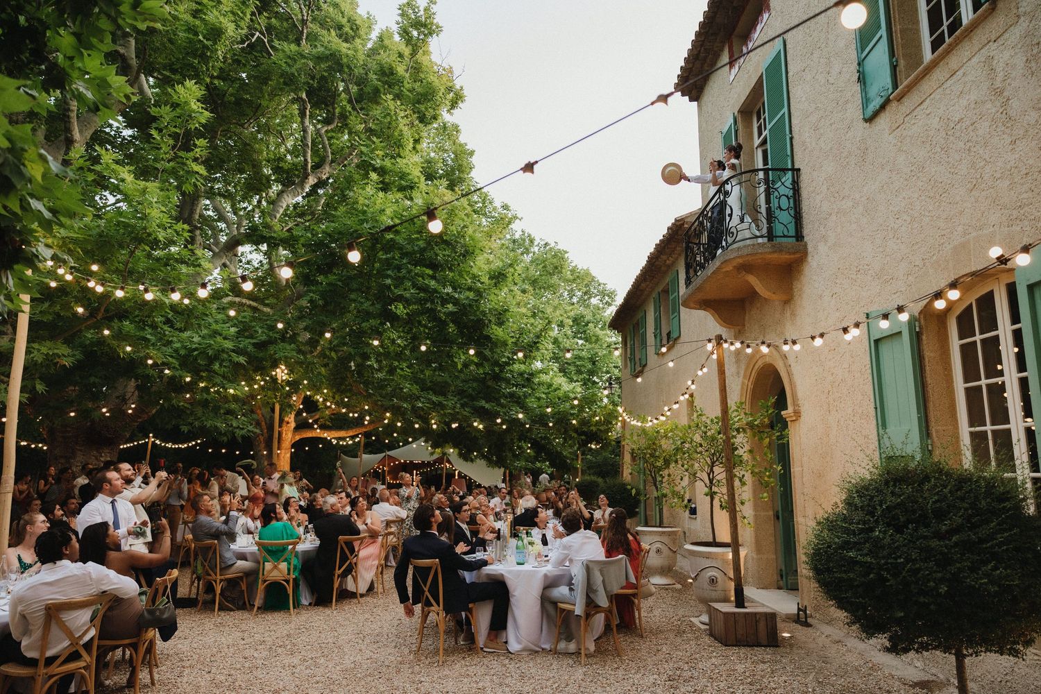 Outdoor wedding reception at a rustic French villa with string lights and dining tables.