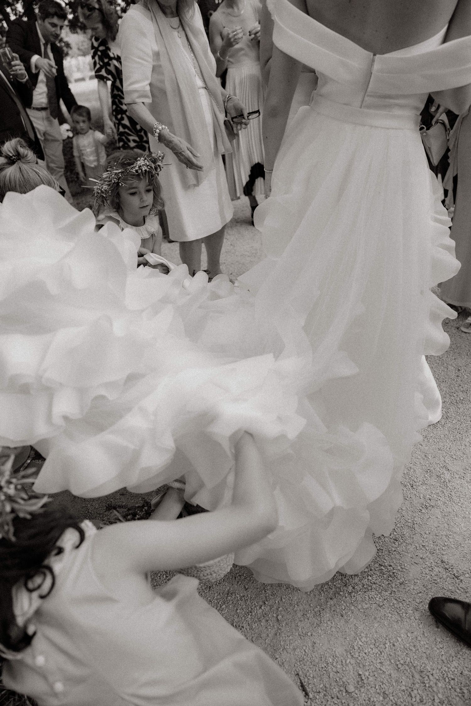 Close-up detail of a white wedding dress train with layers of ruffled fabric flowing across the floor.