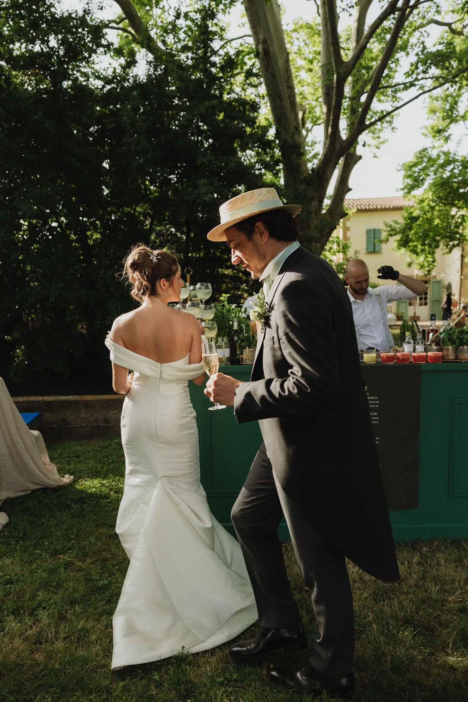 Couple dancing together at an outdoor wedding reception surrounded by greenery.