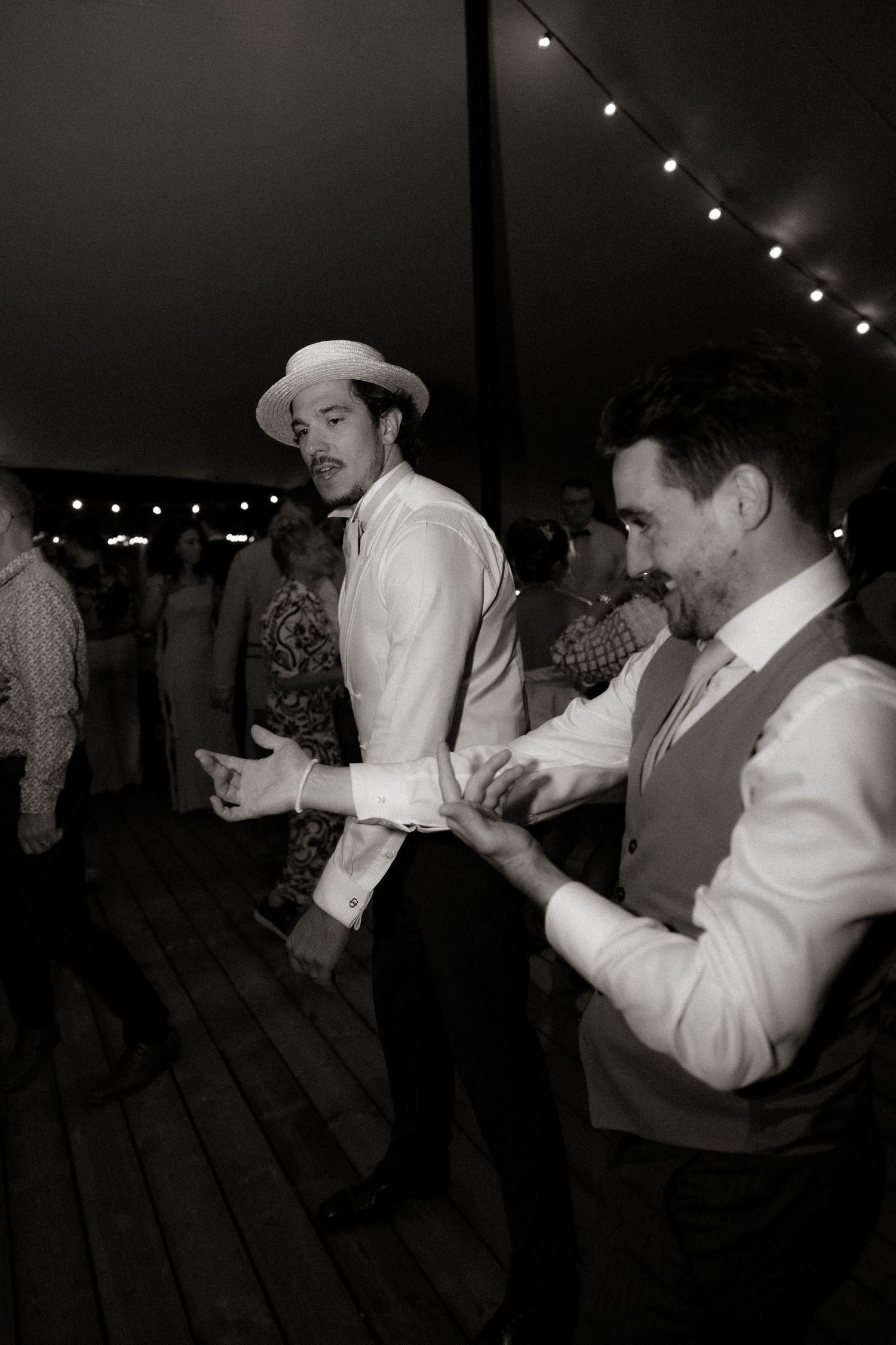 Wedding guests dancing at an evening reception under string lights.