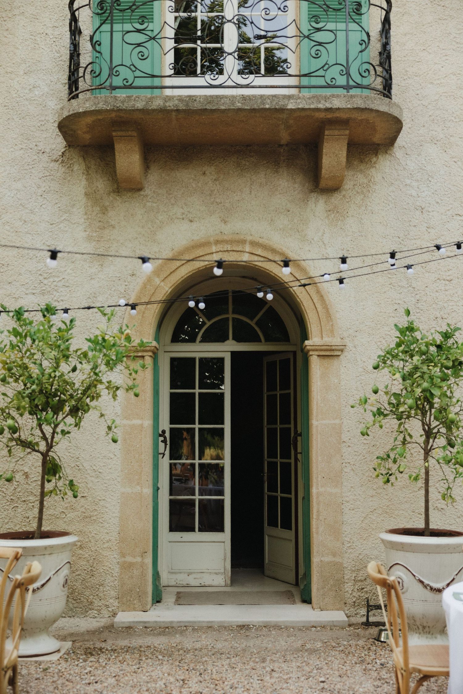 Mediterranean style villa exterior with turquoise shutters and arched doorways.