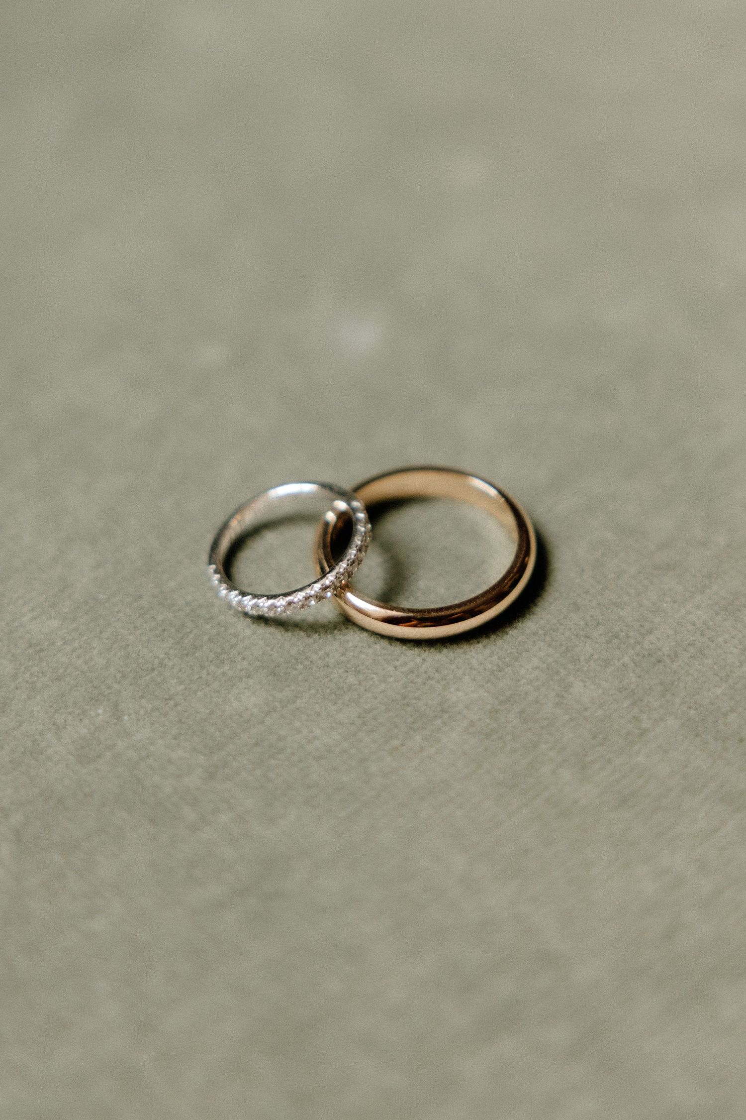 Wedding rings arranged on a neutral gray surface showing elegant diamond and gold bands.