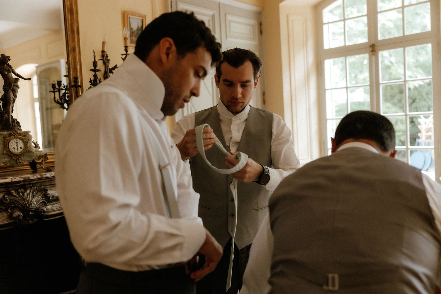 People in white chef coats gather around a table in a bright kitchen setting for a culinary demonstration.