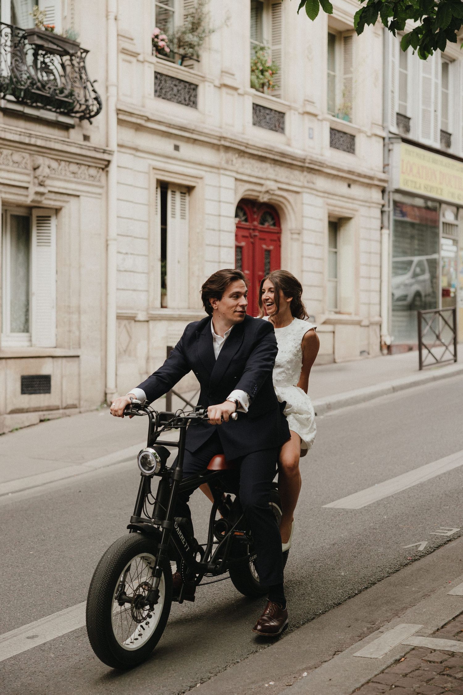 A stylish couple shares intimate moments on vintage motorcycles along a charming Parisian street.