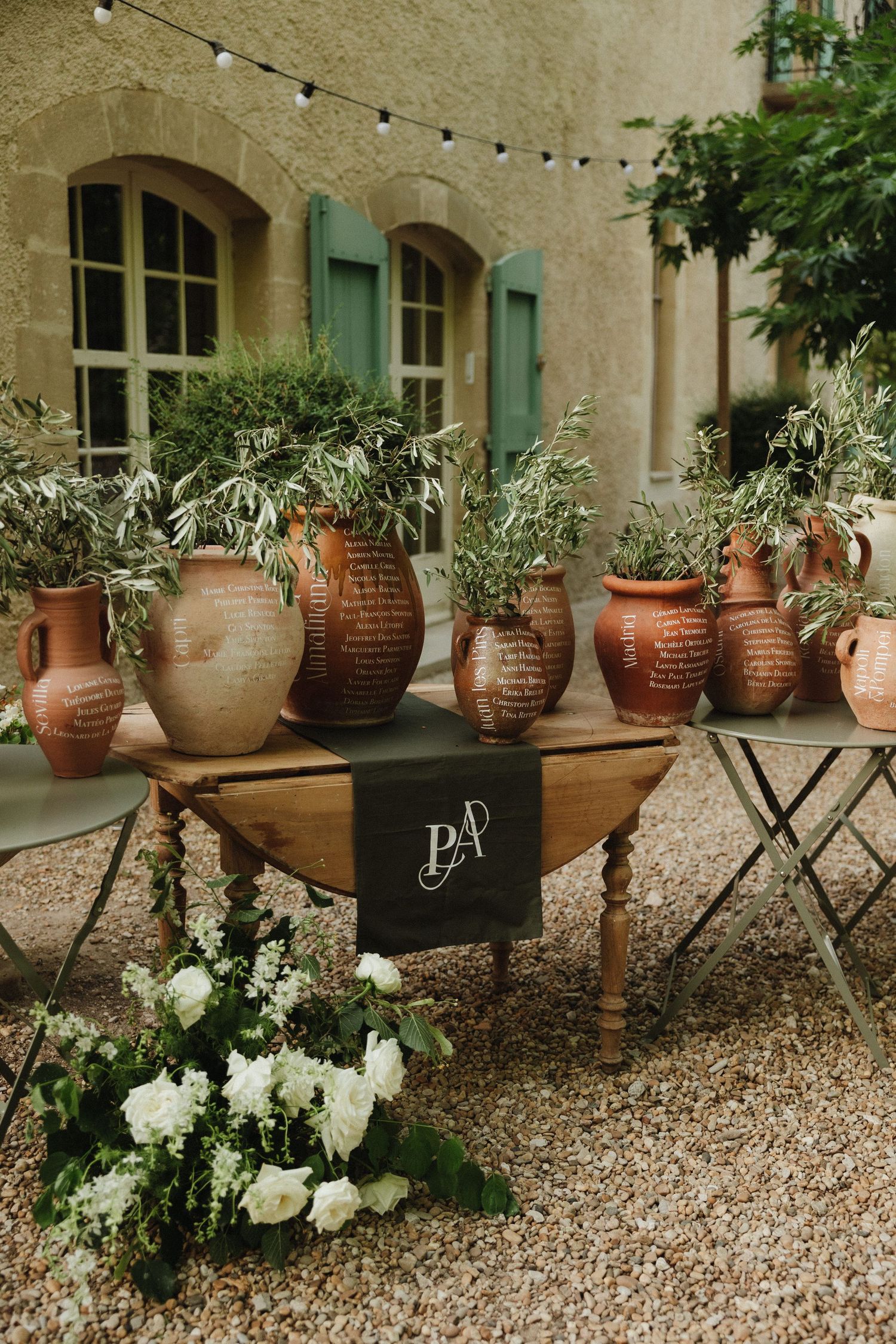 Garden decor featuring terracotta pots with plants along a stone wall with green shutters.