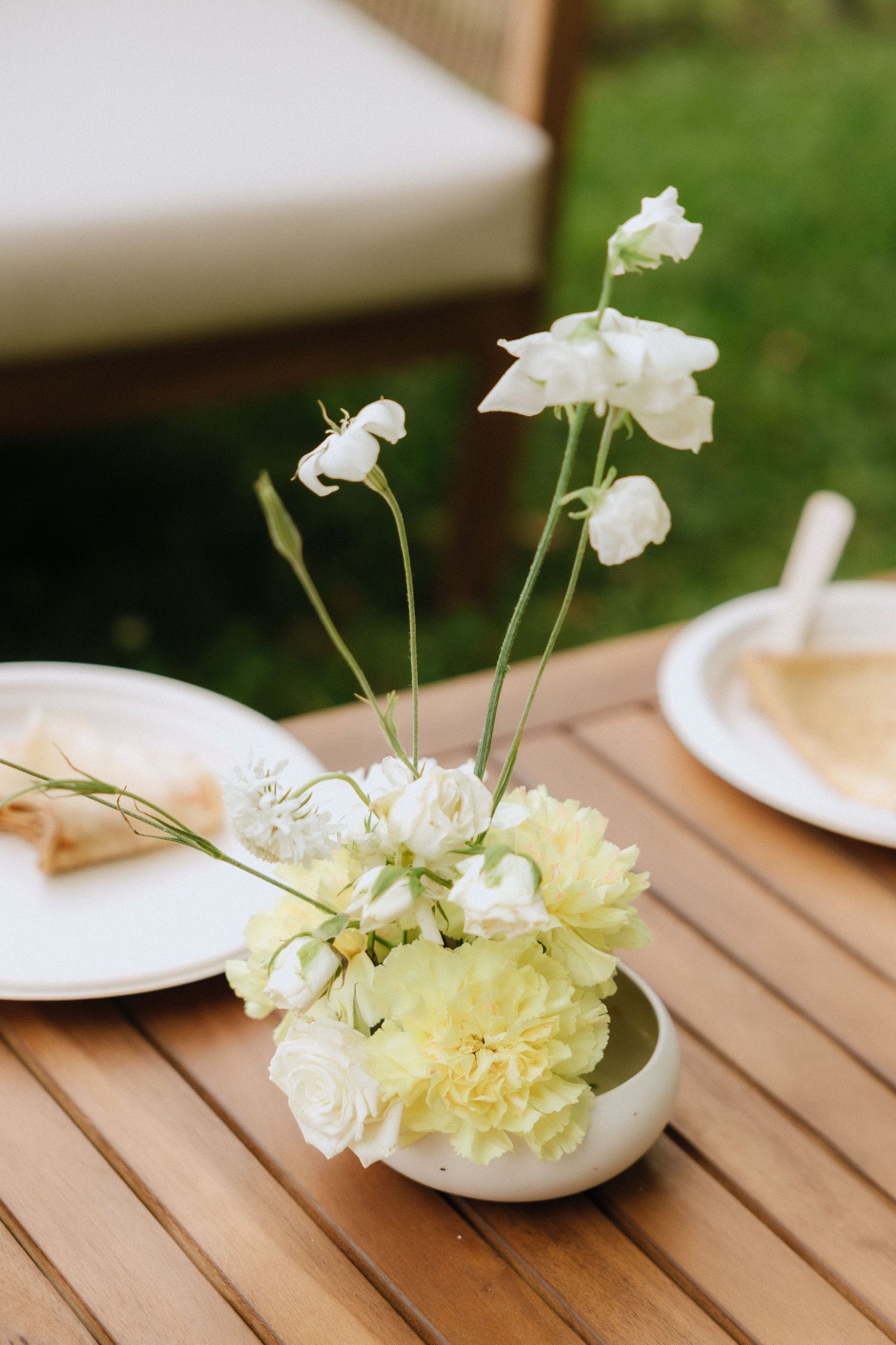 Delicate white and yellow floral centerpieces displayed on wooden tables.
