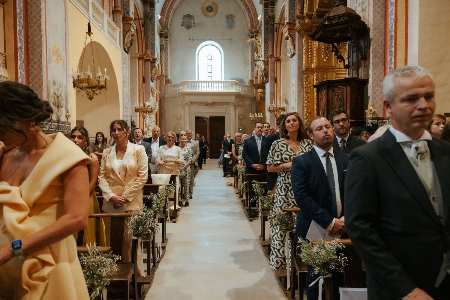 Wedding ceremony in a grand cathedral with ornate architecture and rows of wooden pews.