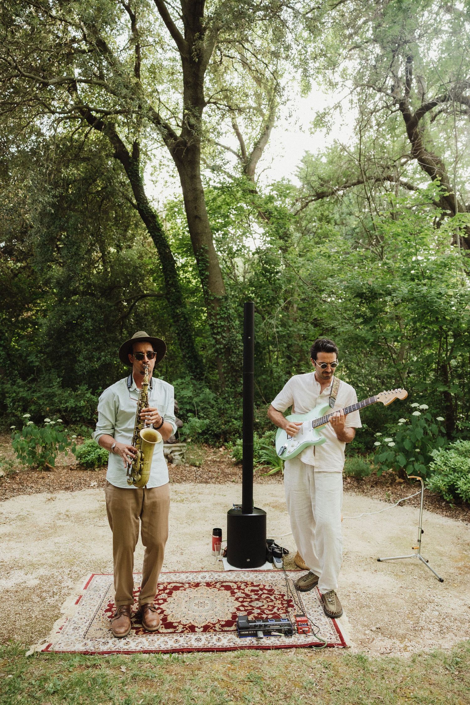 A couple dancing on a decorative rug outdoors surrounded by trees and greenery.