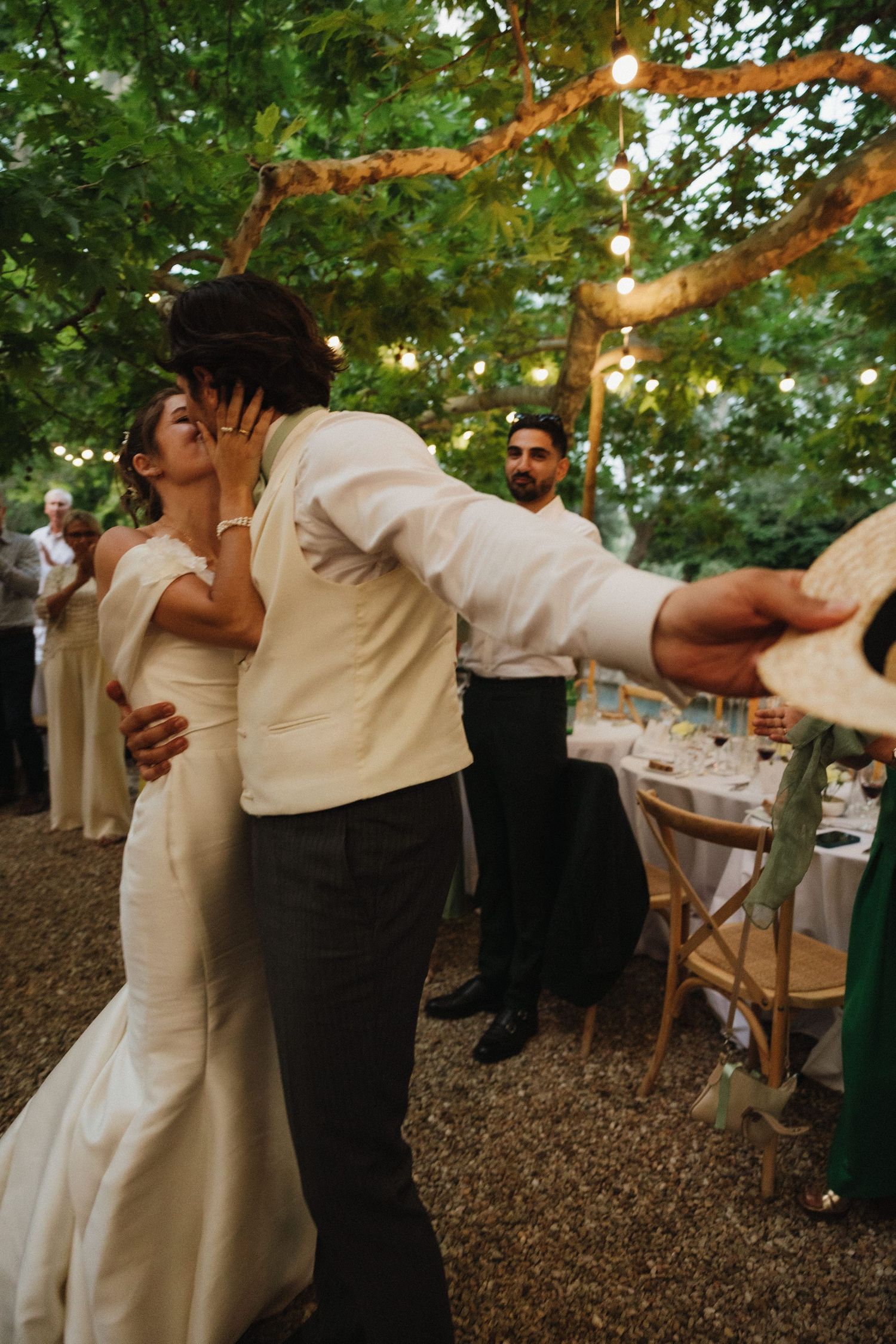 An intimate dance moment at an outdoor wedding reception under string lights and trees.
