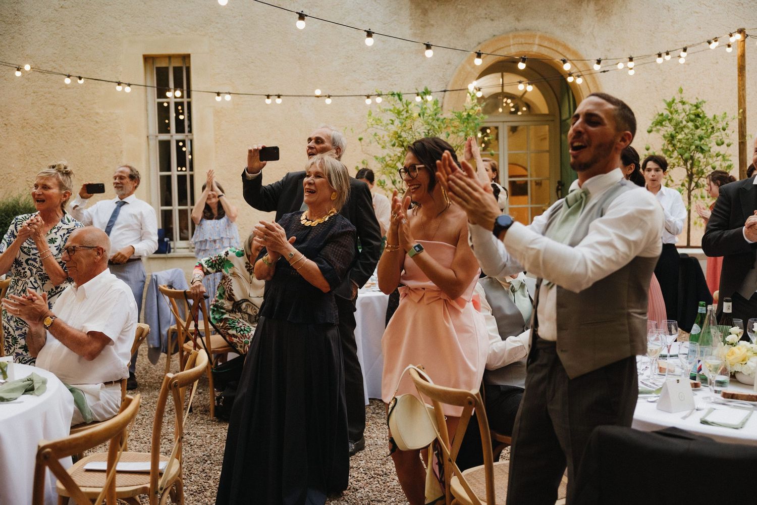 Wedding reception in a rustic venue with string lights and guests celebrating.
