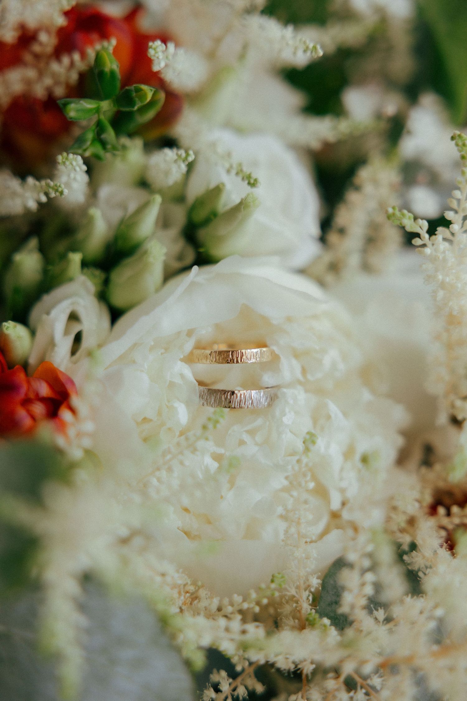 Wedding rings nestled within white roses and delicate baby's breath flowers in a romantic bridal bouquet.
