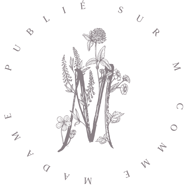 Delicate botanical illustration featuring a floral letter M composed of wildflowers and stems in a circular text frame.