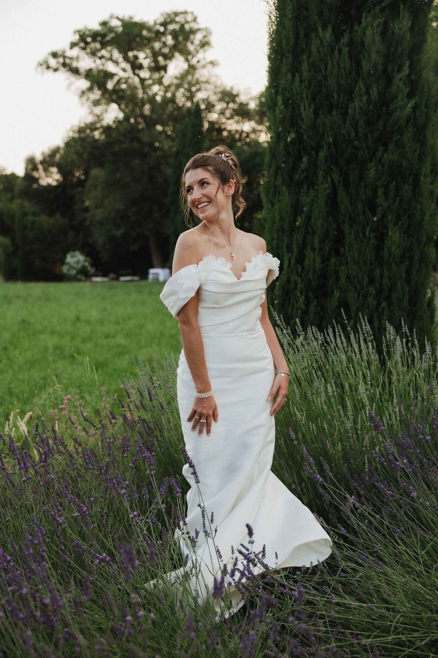 A white wedding dress flowing among blooming lavender plants in a garden setting.