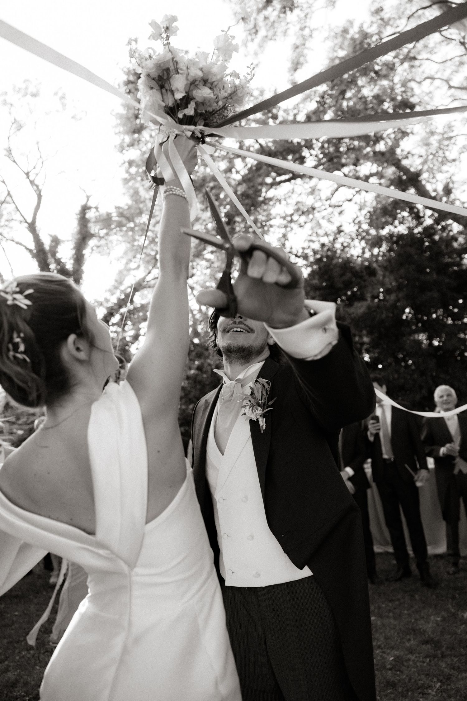 Black and white photos of joyful wedding celebration with streamers and dancing outdoors.