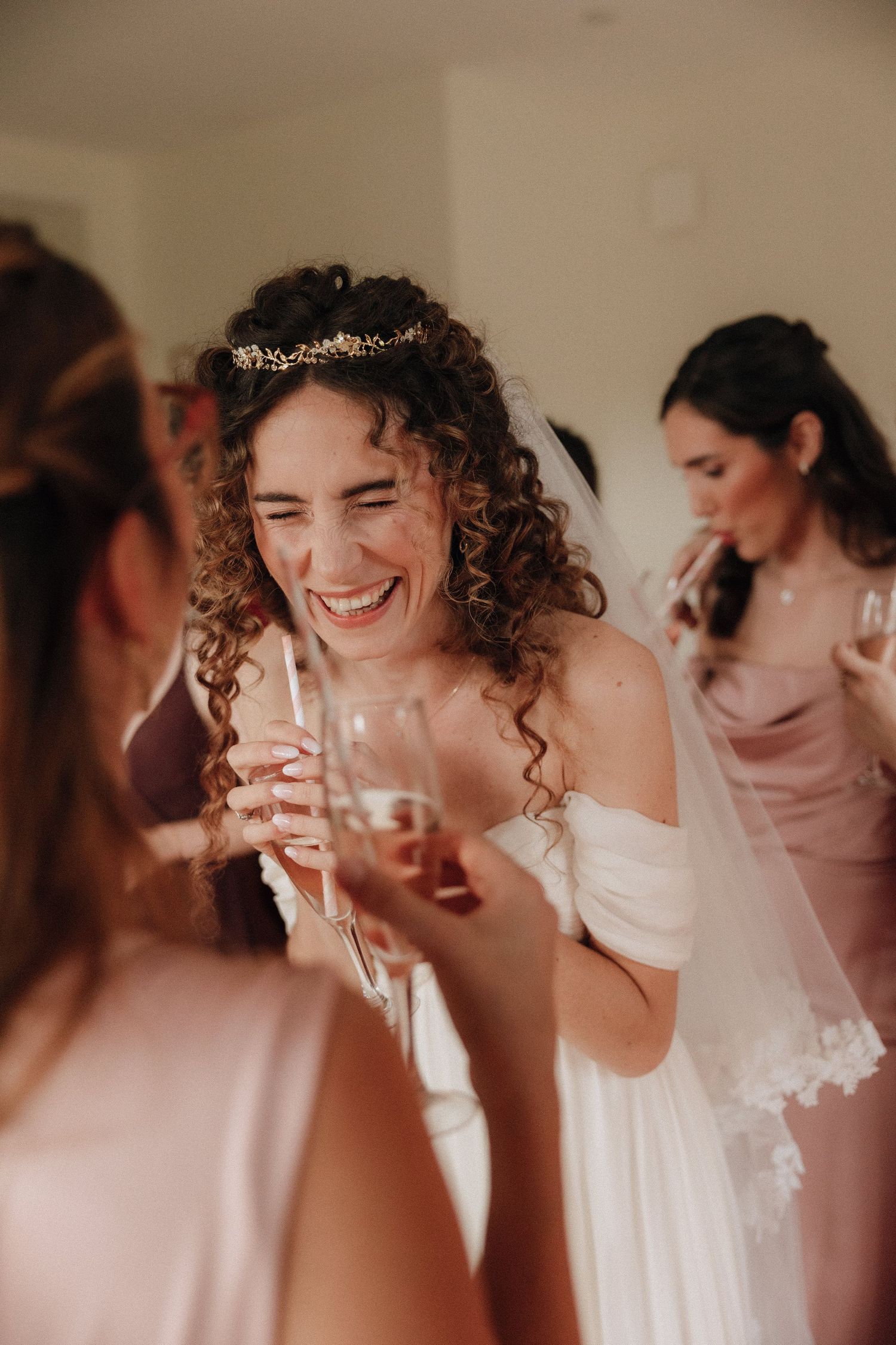 A bride wearing a white dress and delicate tiara shares a joyful moment with guests during her wedding celebration.