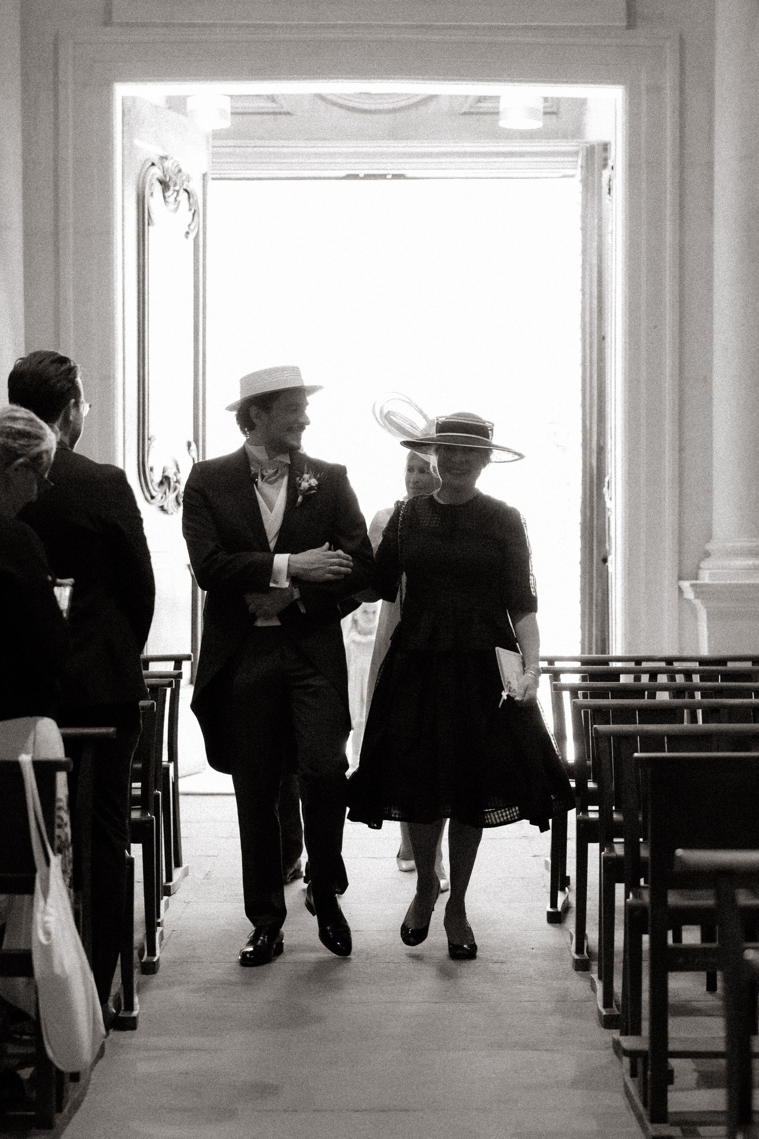 Black and white photo series of people gathering in a formal indoor setting with benches.