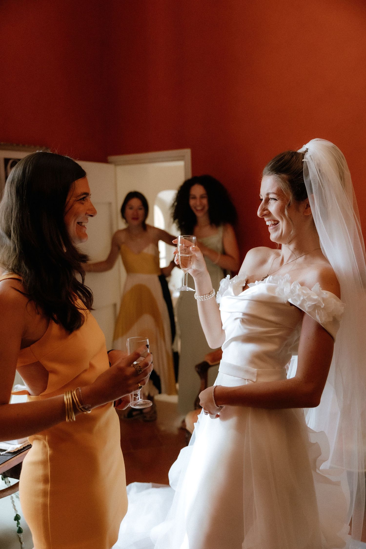Wedding party members in white dresses share joyful moments during pre-ceremony preparations.