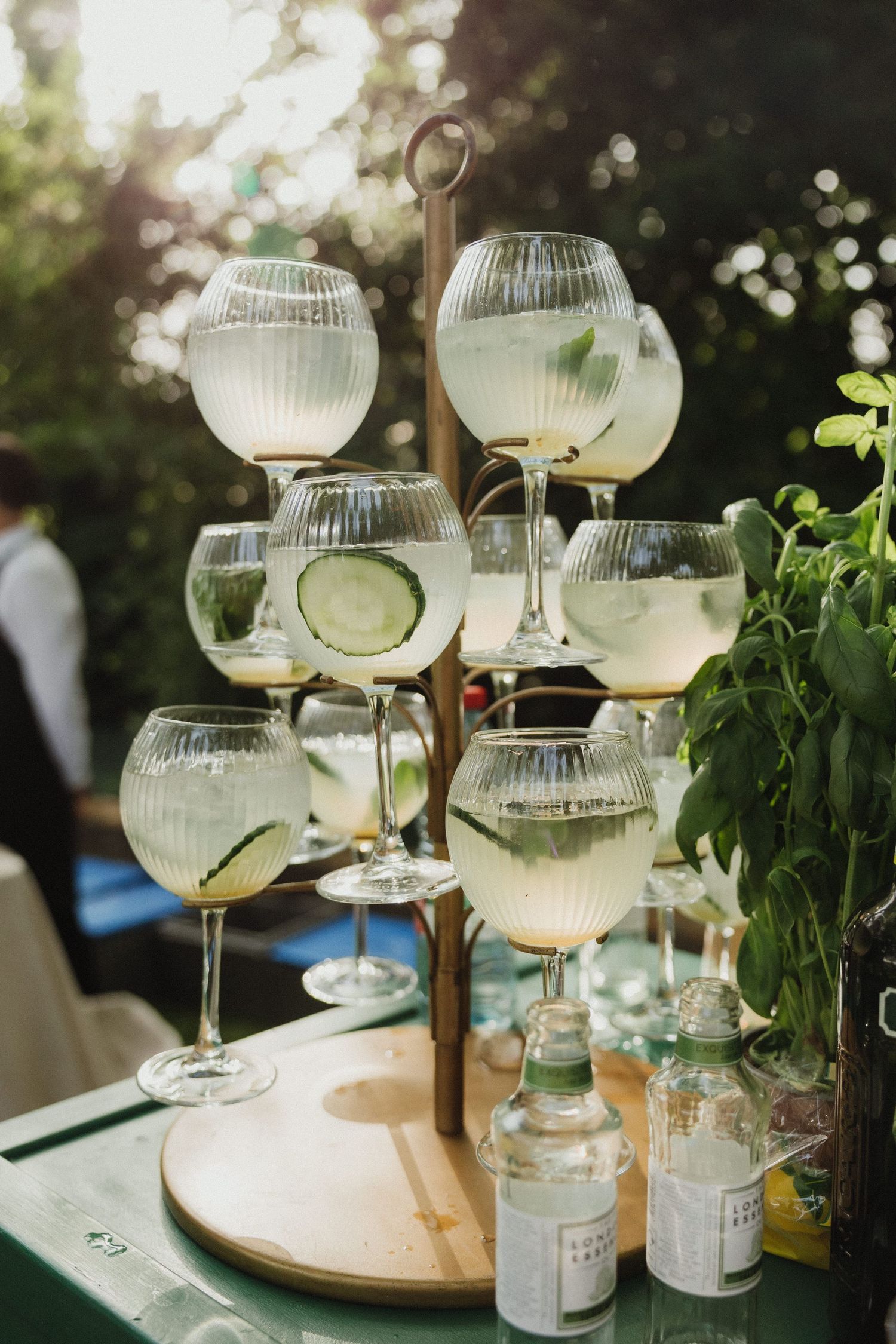 Elegant coupe champagne glasses arranged on a wooden stand with decorative lighting in an outdoor setting.